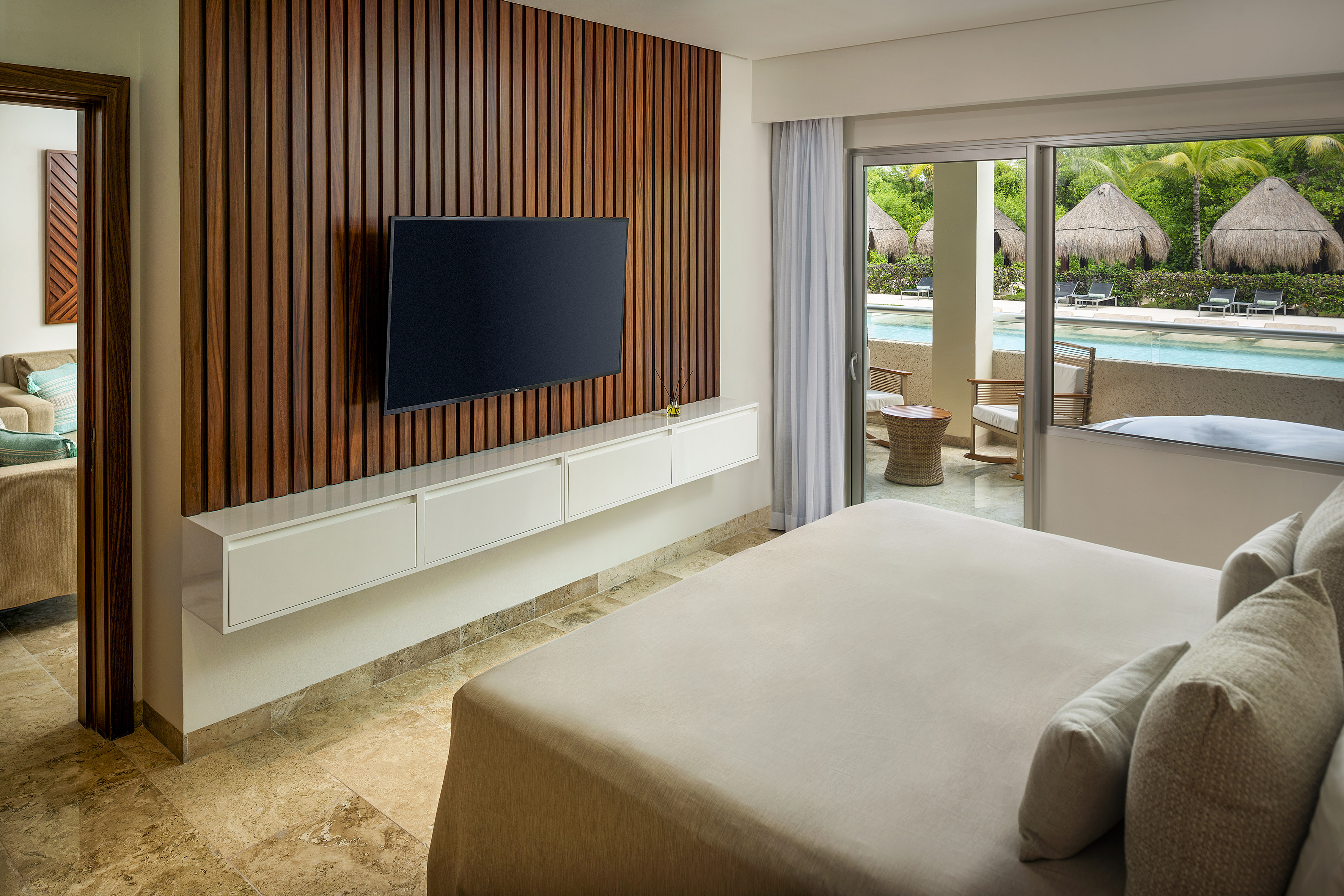 Tropical resort bedroom with pool view, modern decor, and wood accent wall.