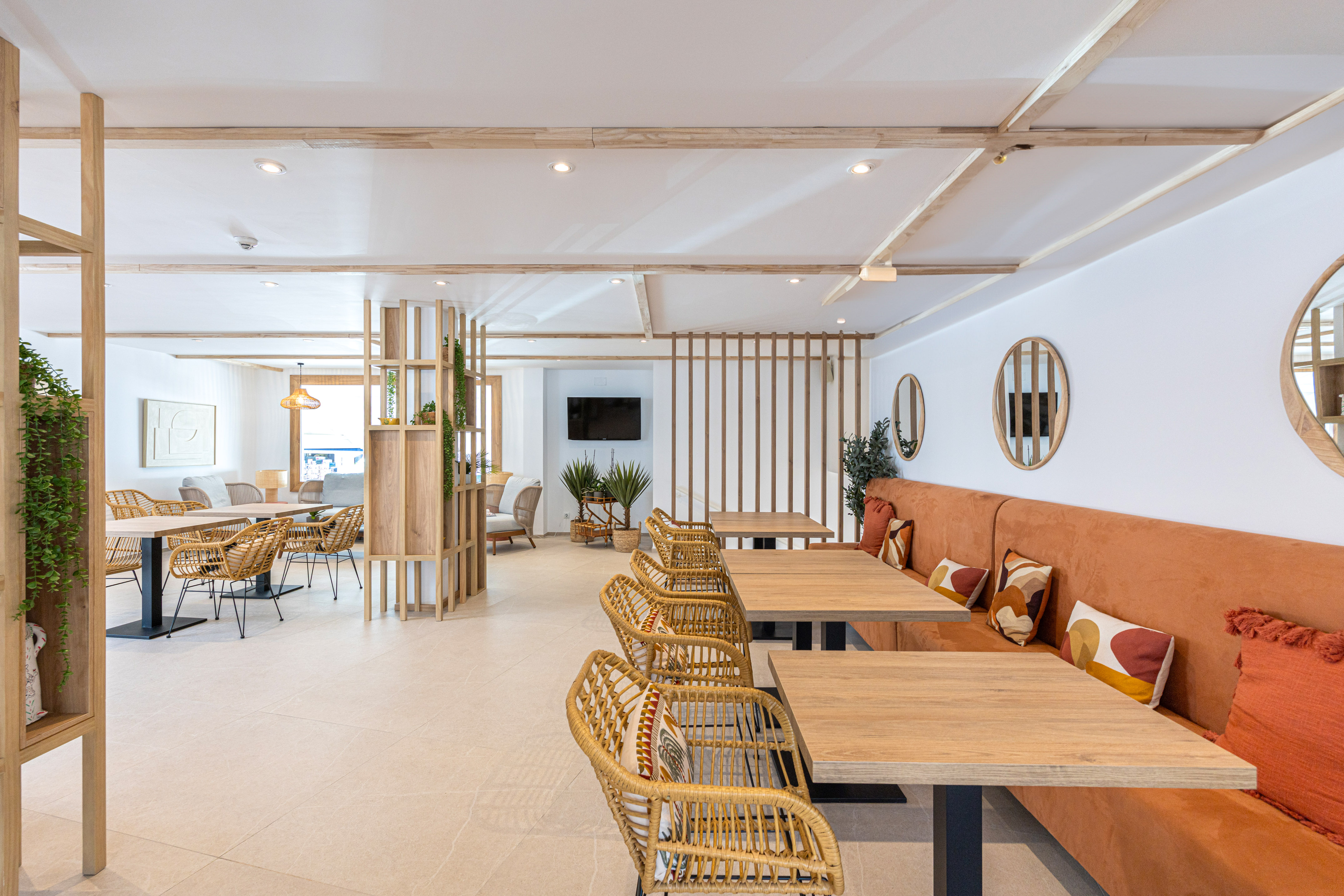 Contemporary lounge with light wood, rattan seating, and orange banquette.