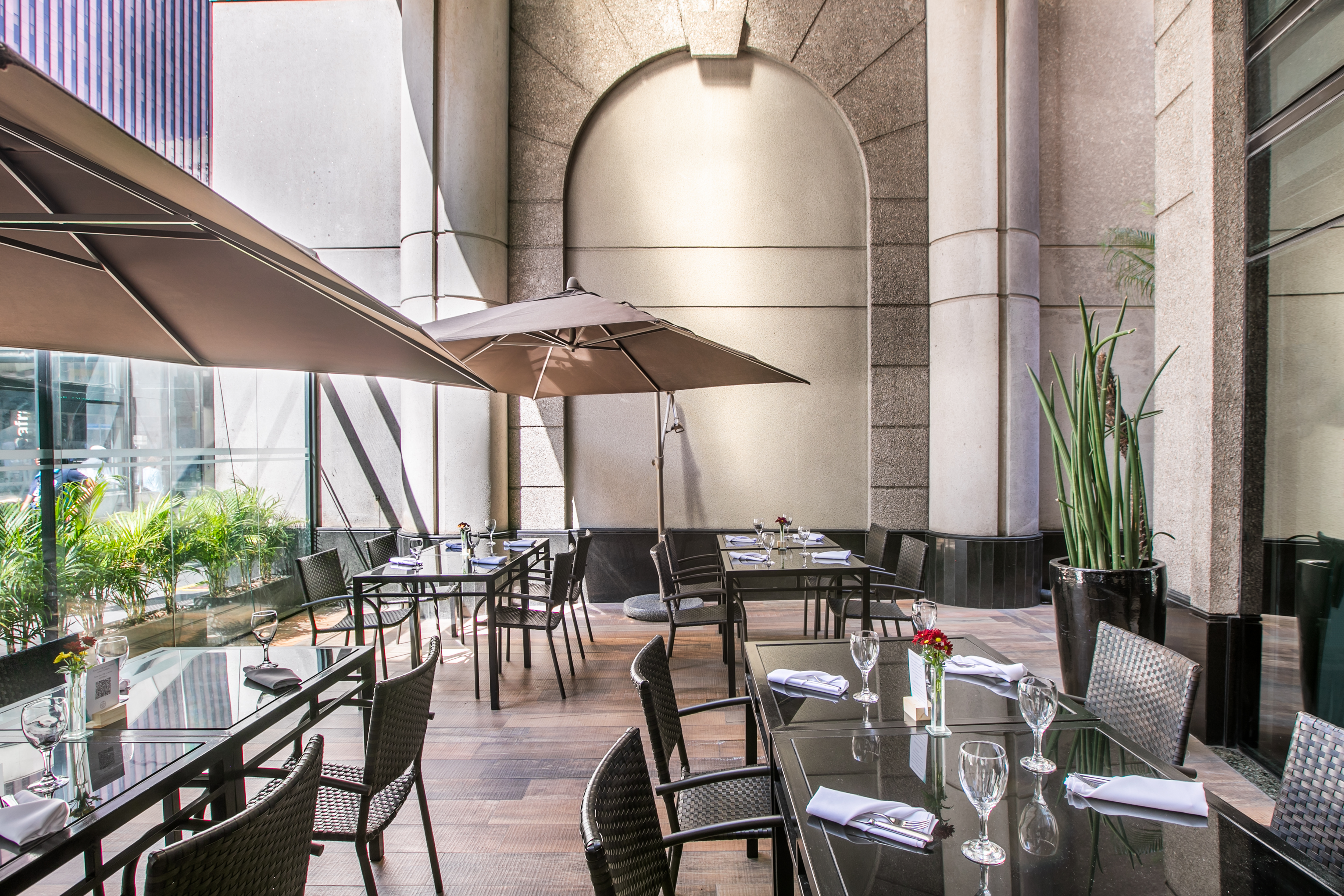 Modern urban building entrance with outdoor patio umbrellas and concrete facade.