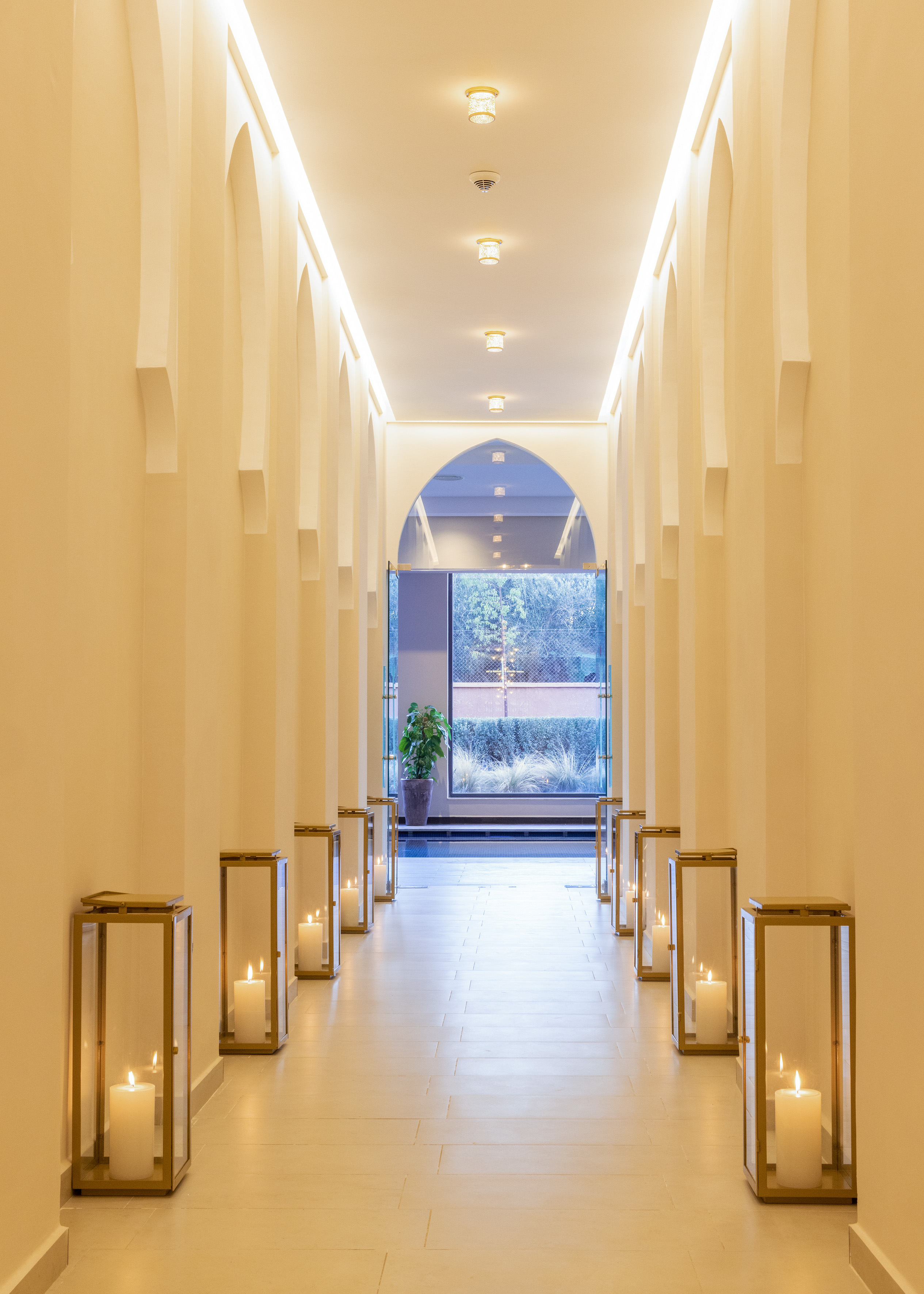 Luxury hotel hallway with arched walls, candle lanterns, and outdoor view.
