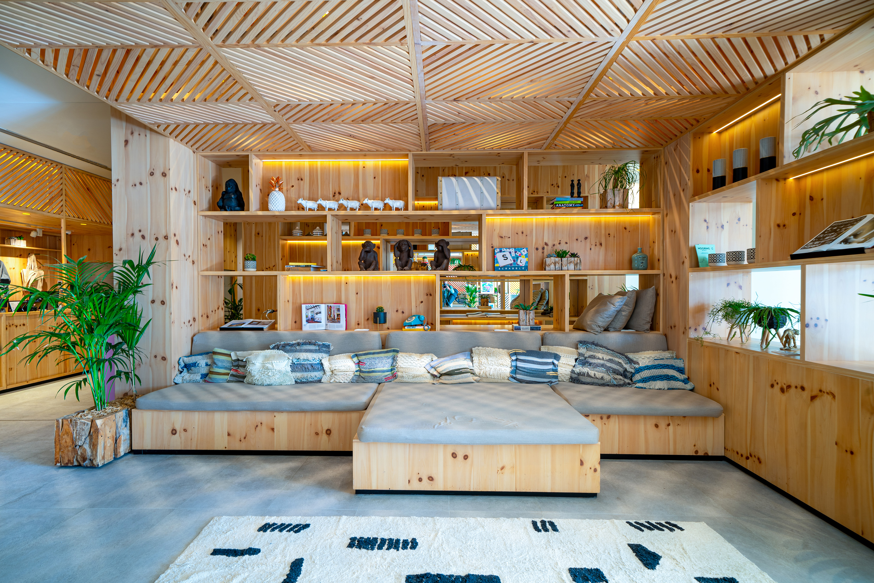 Stylish natural wood lounge with illuminated shelves, built-in seating, and modern decor.