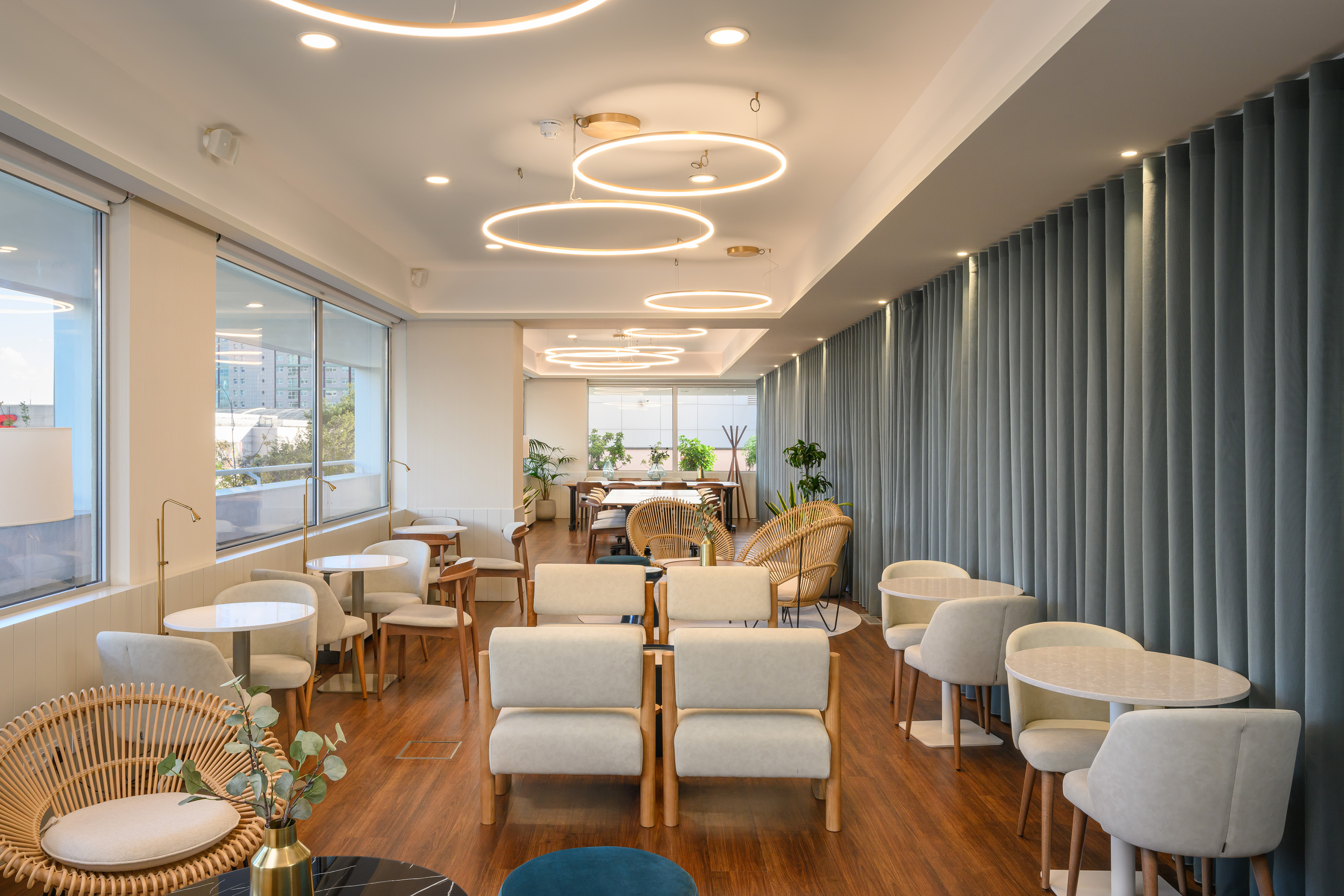 Modern office lounge with circular lights, diverse seating, and large windows.