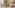 Elegant classic hotel bedroom with upholstered bed, toile curtains, and wooden chair.