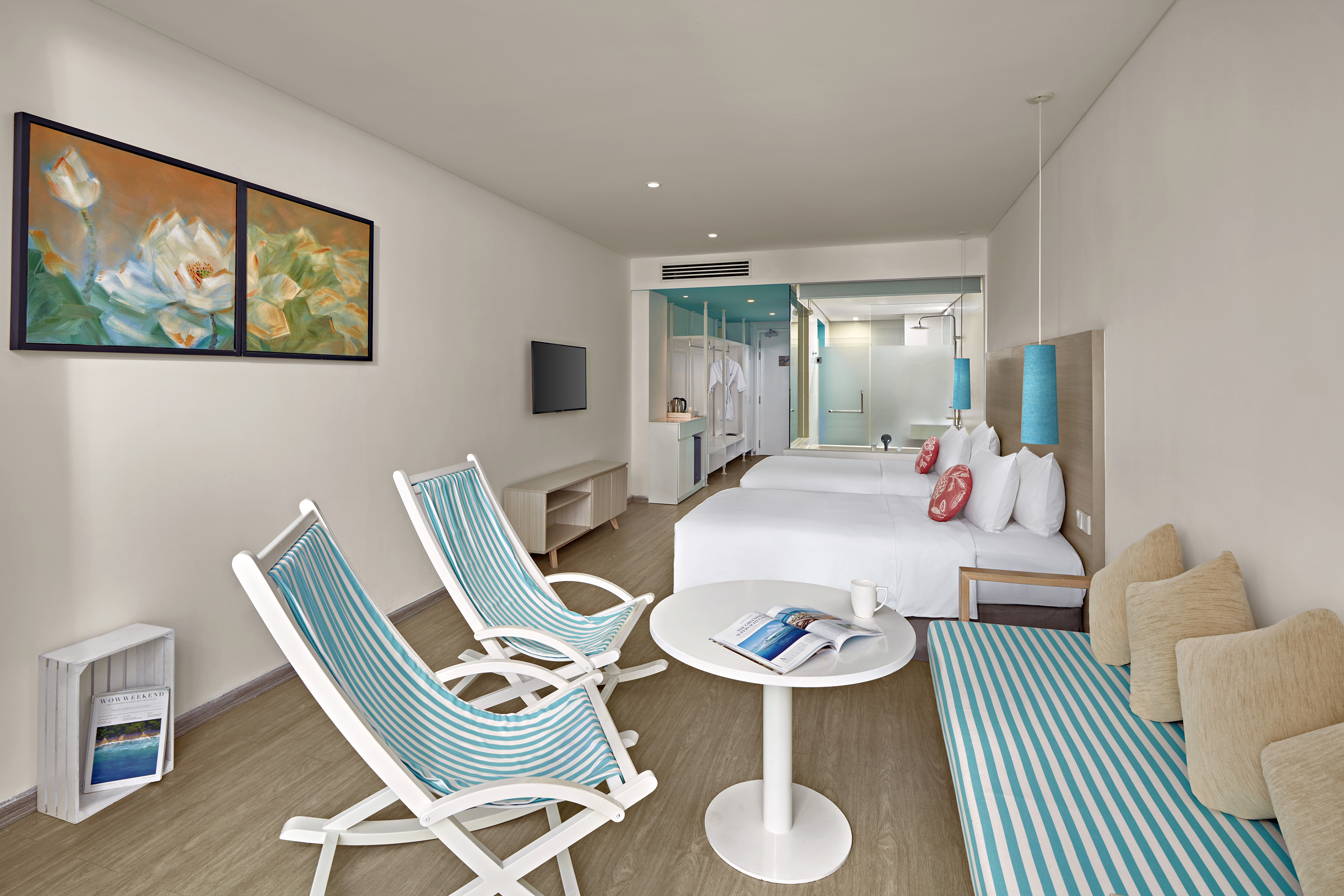 Stylish resort room featuring twin beds, striped seating, and turquoise accents.