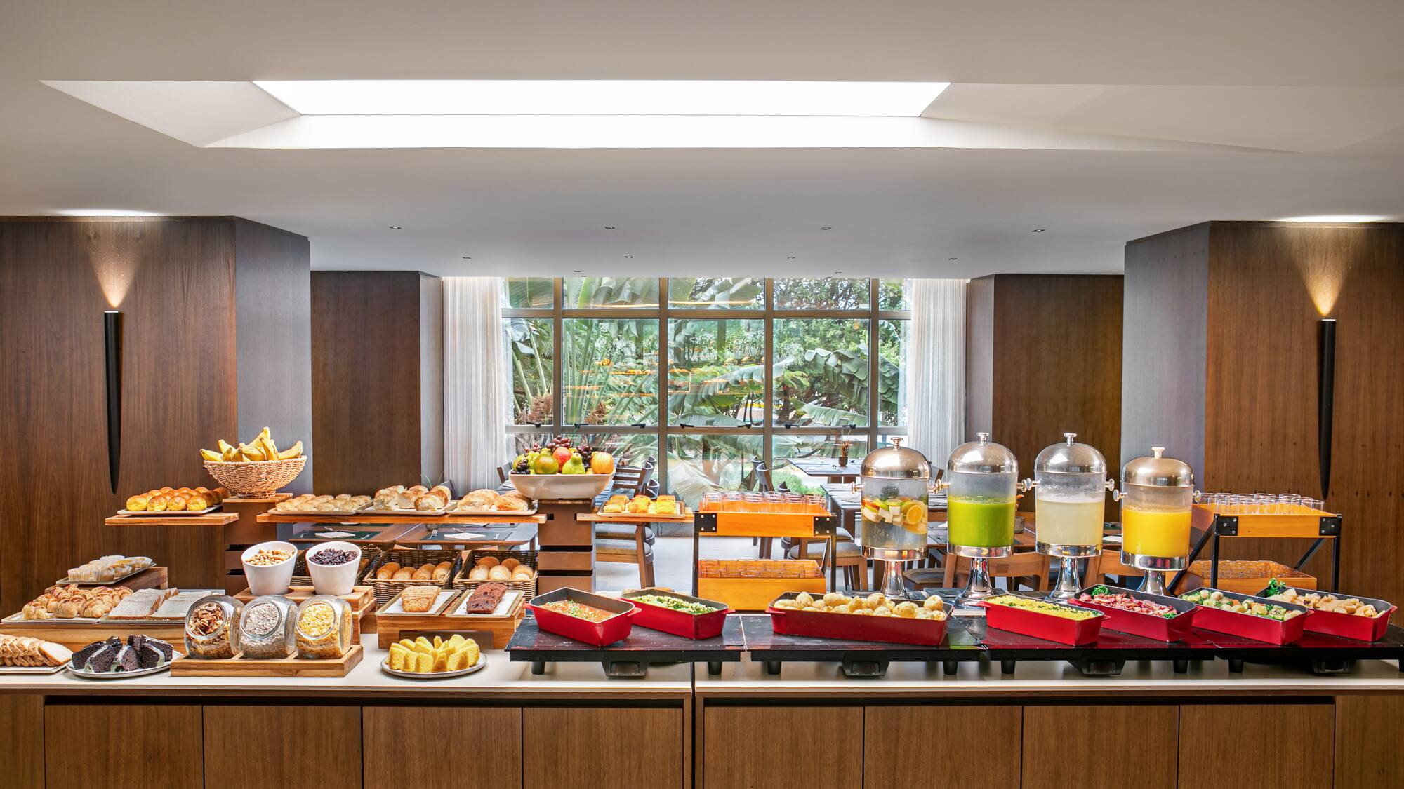 Modern hotel breakfast buffet with pastries, fruit, juices, and hot food.