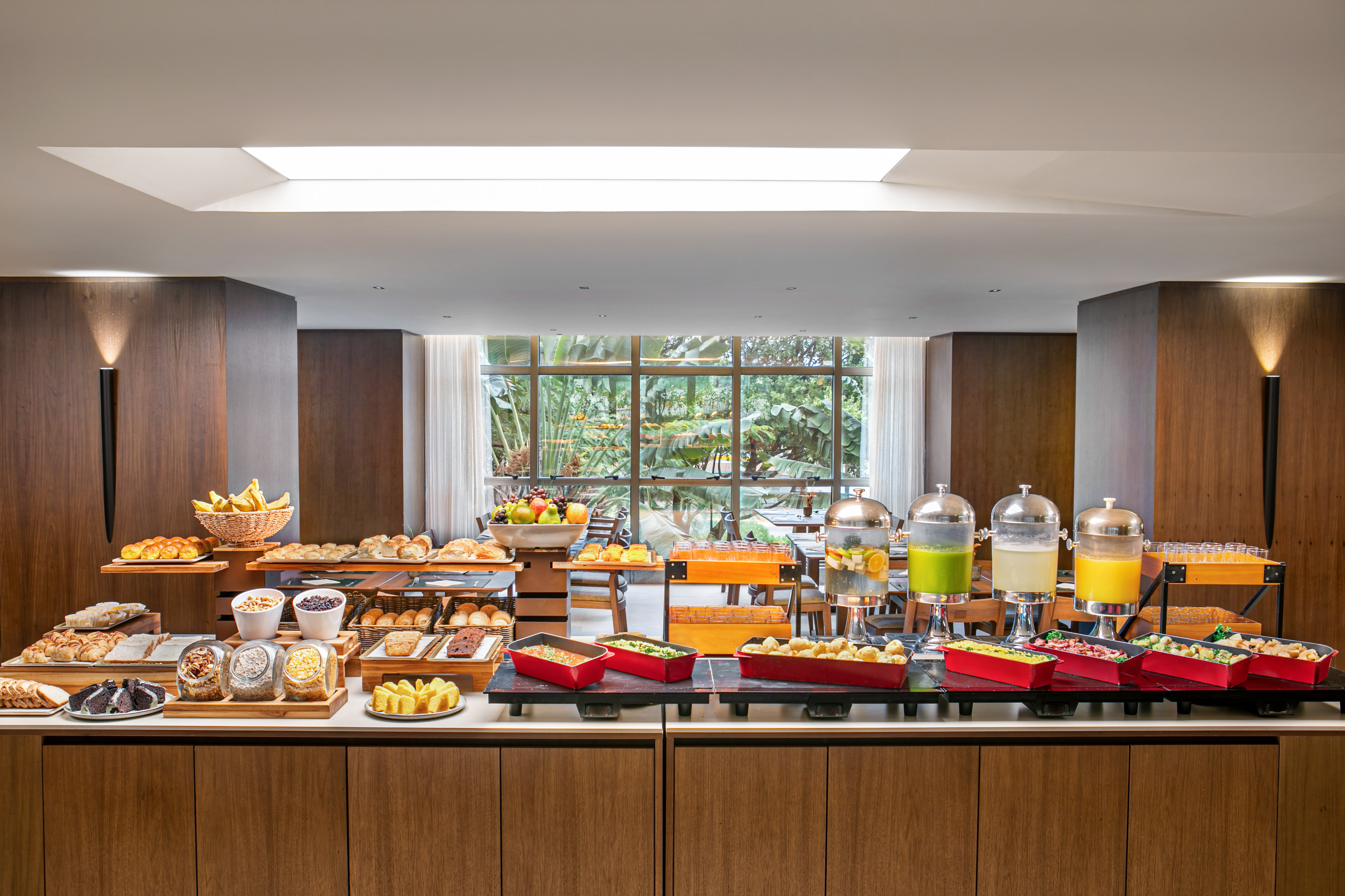 Modern hotel breakfast buffet with pastries, fruit, juices, and hot food.