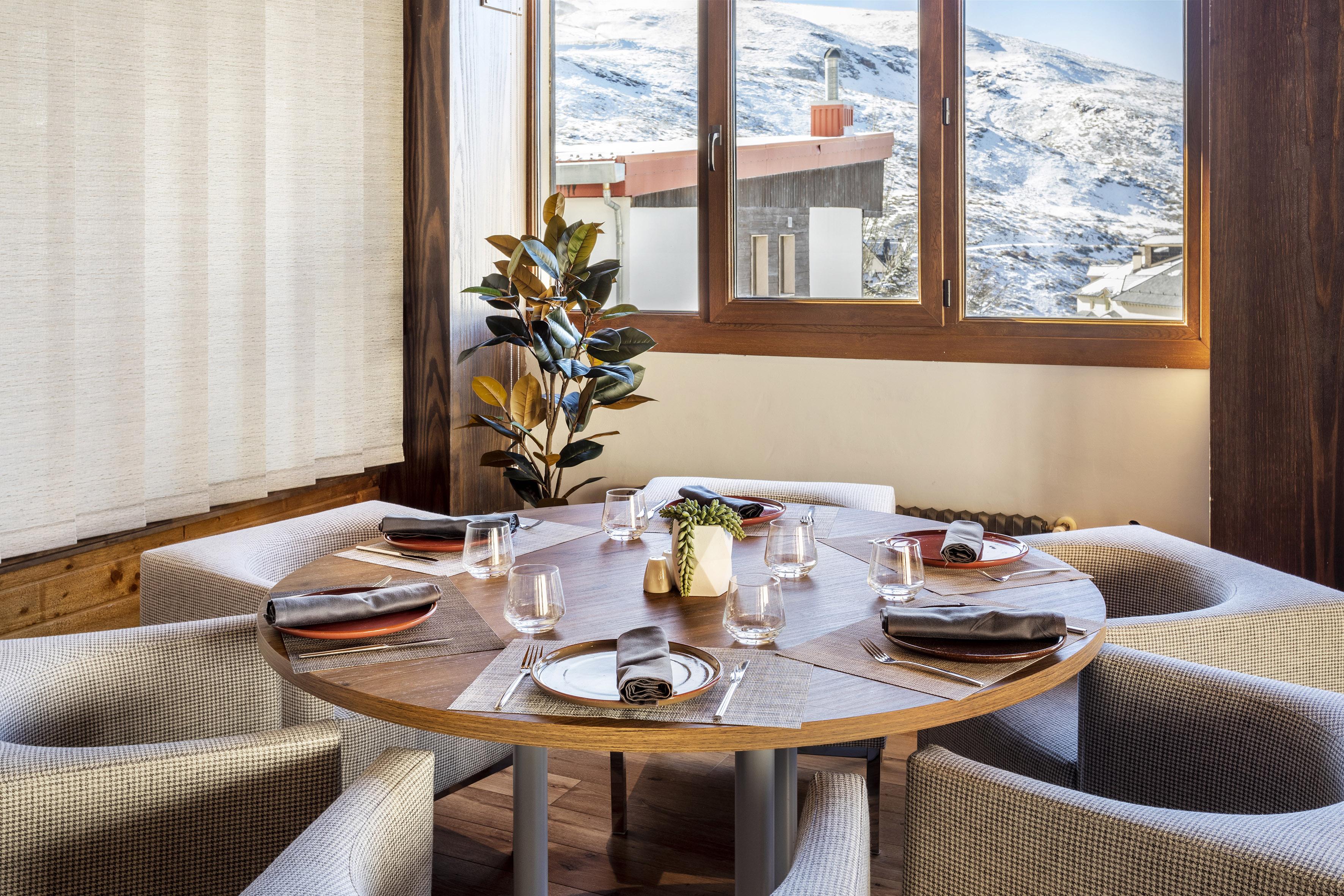 Cozy restaurant dining table with snowy mountain view from window.