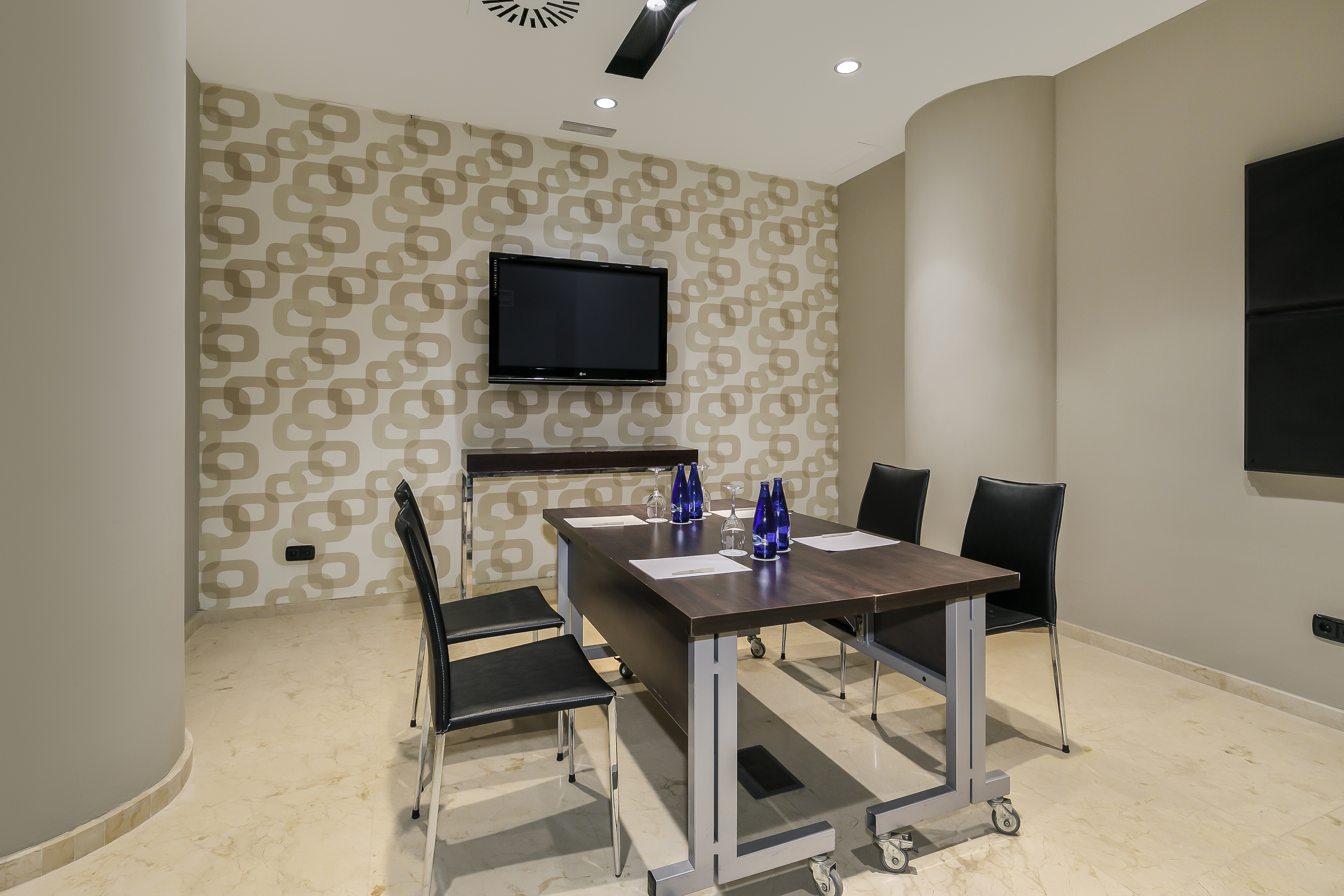 Modern meeting room with dark wooden table, black chairs, and wall-mounted TV.