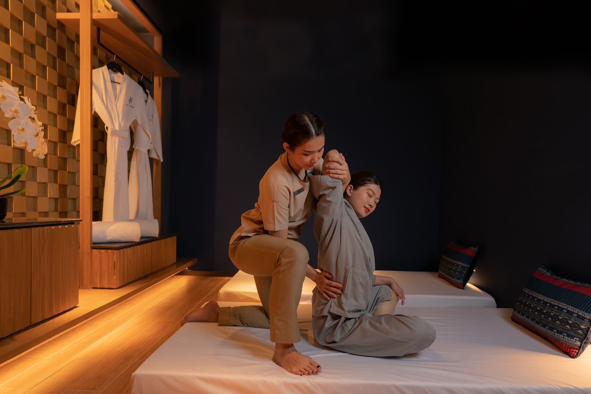 Massage therapist stretching client in a serene spa room.