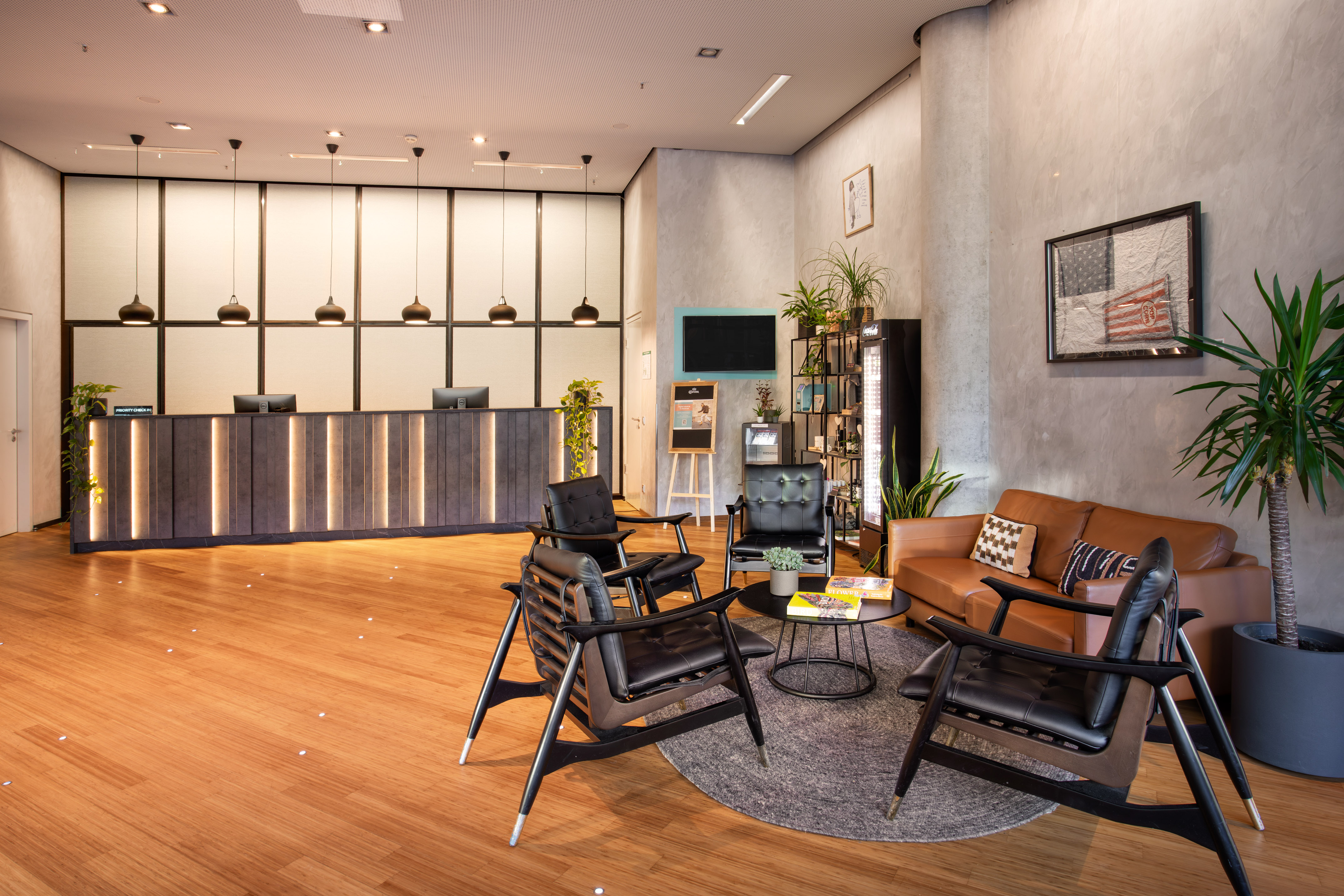 Hotel reception area with sleek desk, comfortable seating, and green plants.