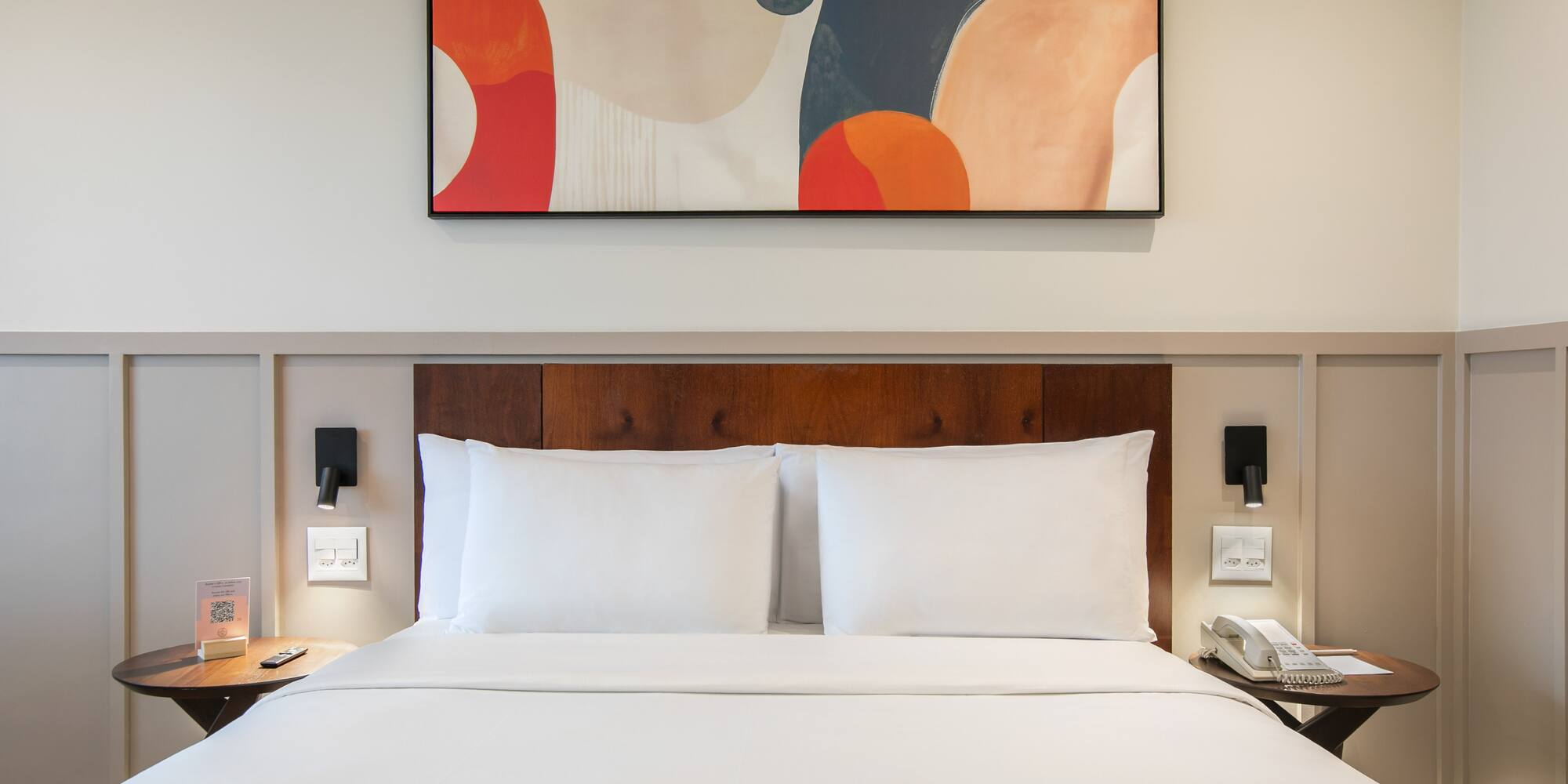 a bed with white sheets and a painting above it