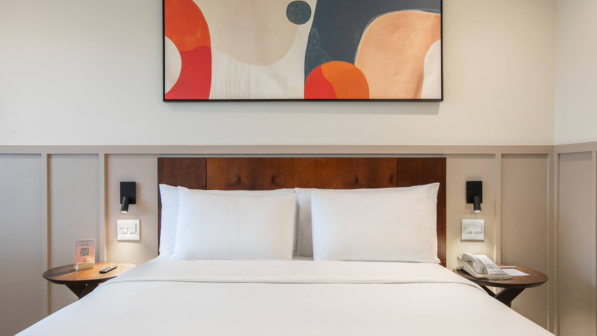 a bed with white sheets and a painting above it