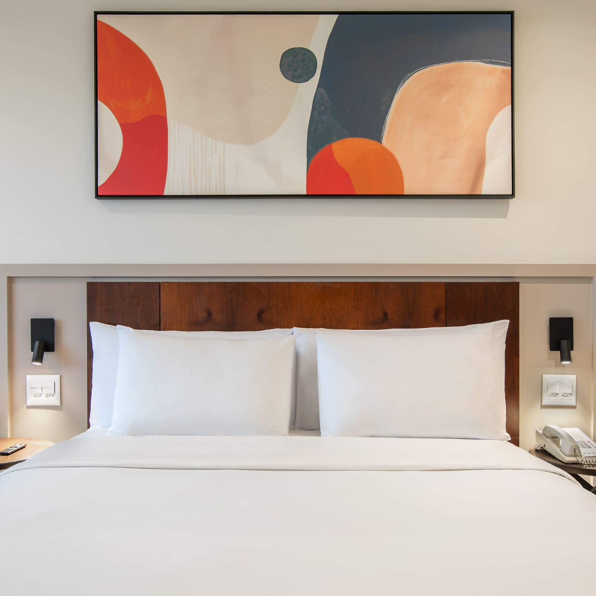 a bed with white sheets and a painting above it