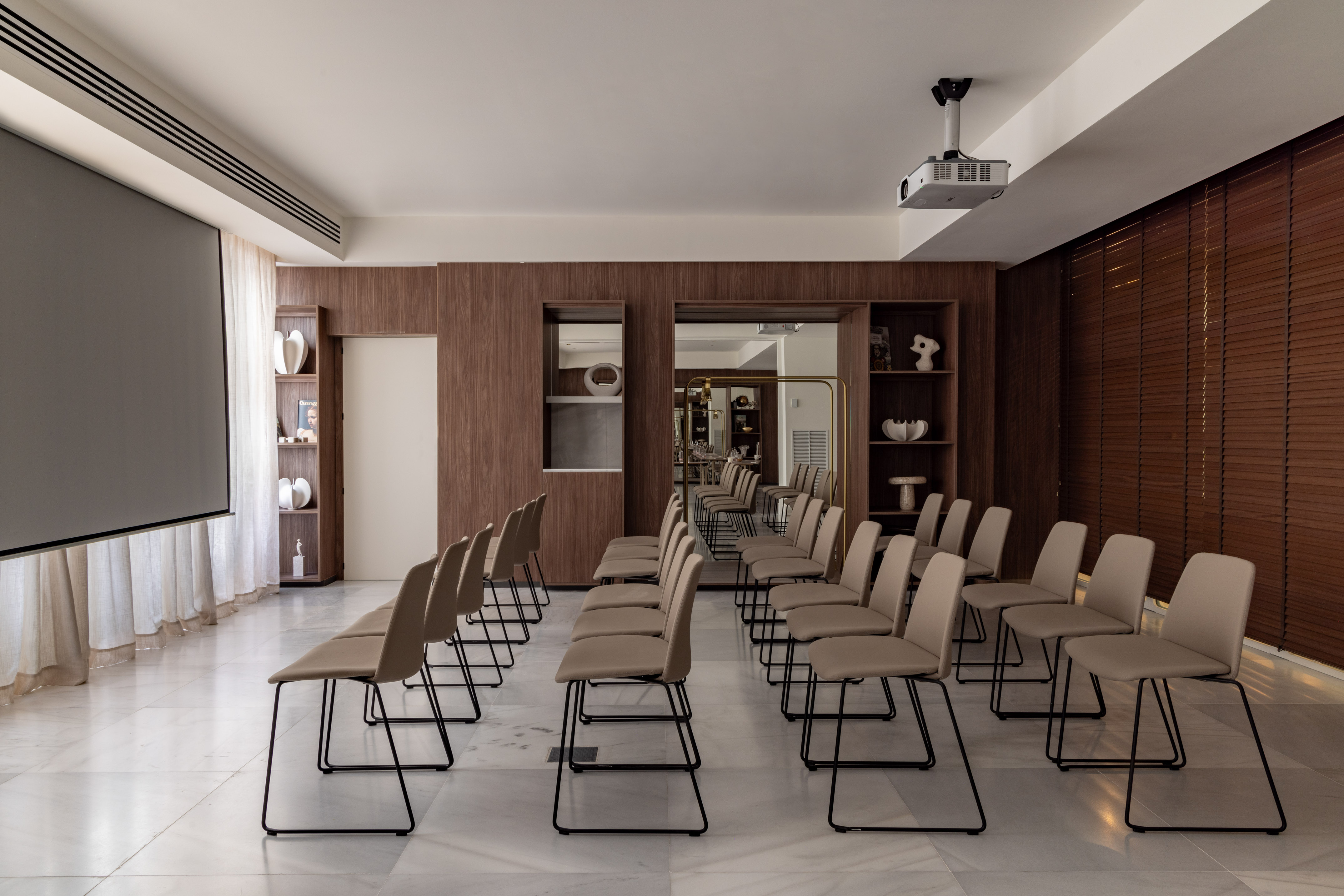 Corporate meeting room with projector screen, beige chairs, and dark wood finishes.