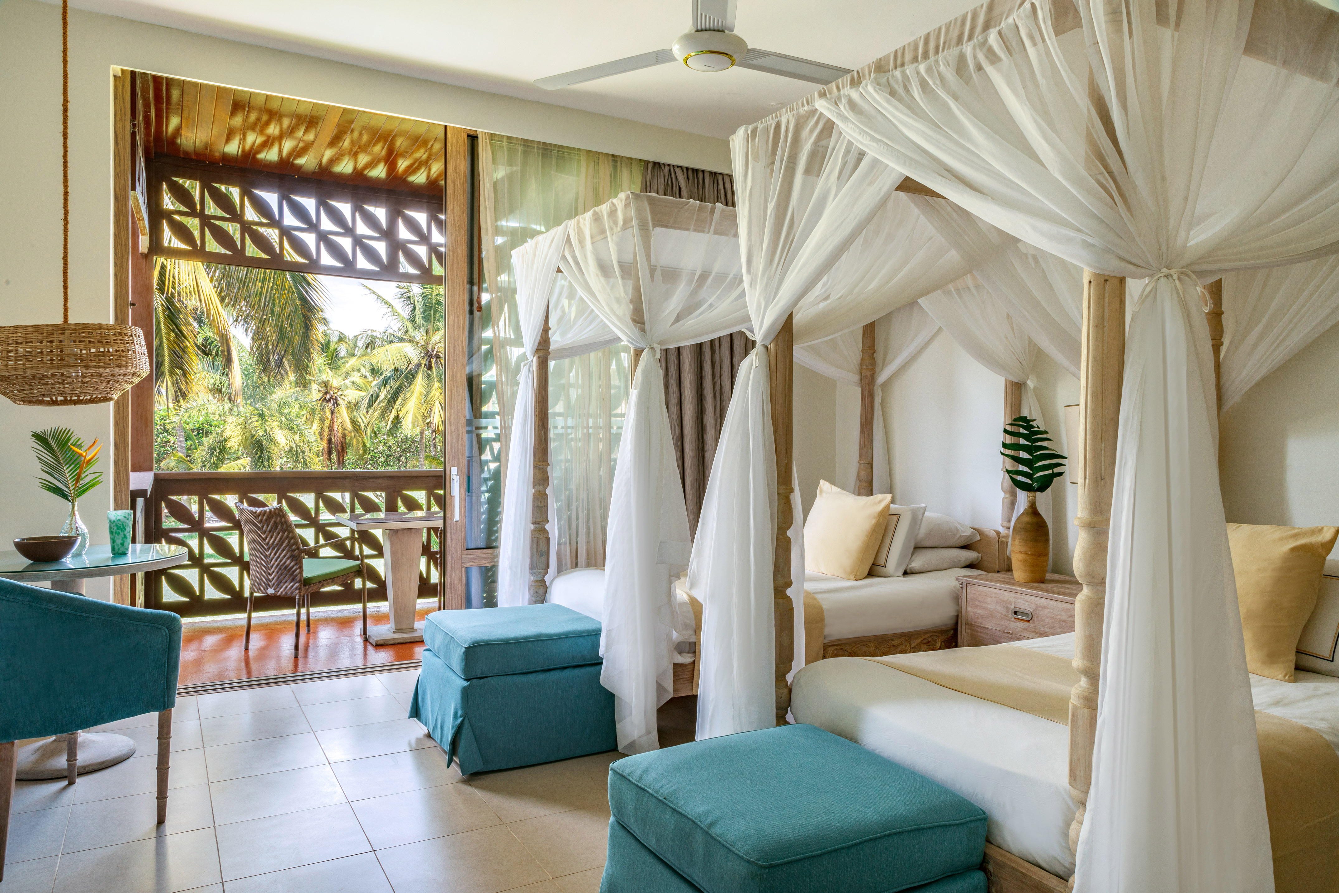 Tropical resort bedroom: two canopy beds, teal furniture, palm tree balcony.