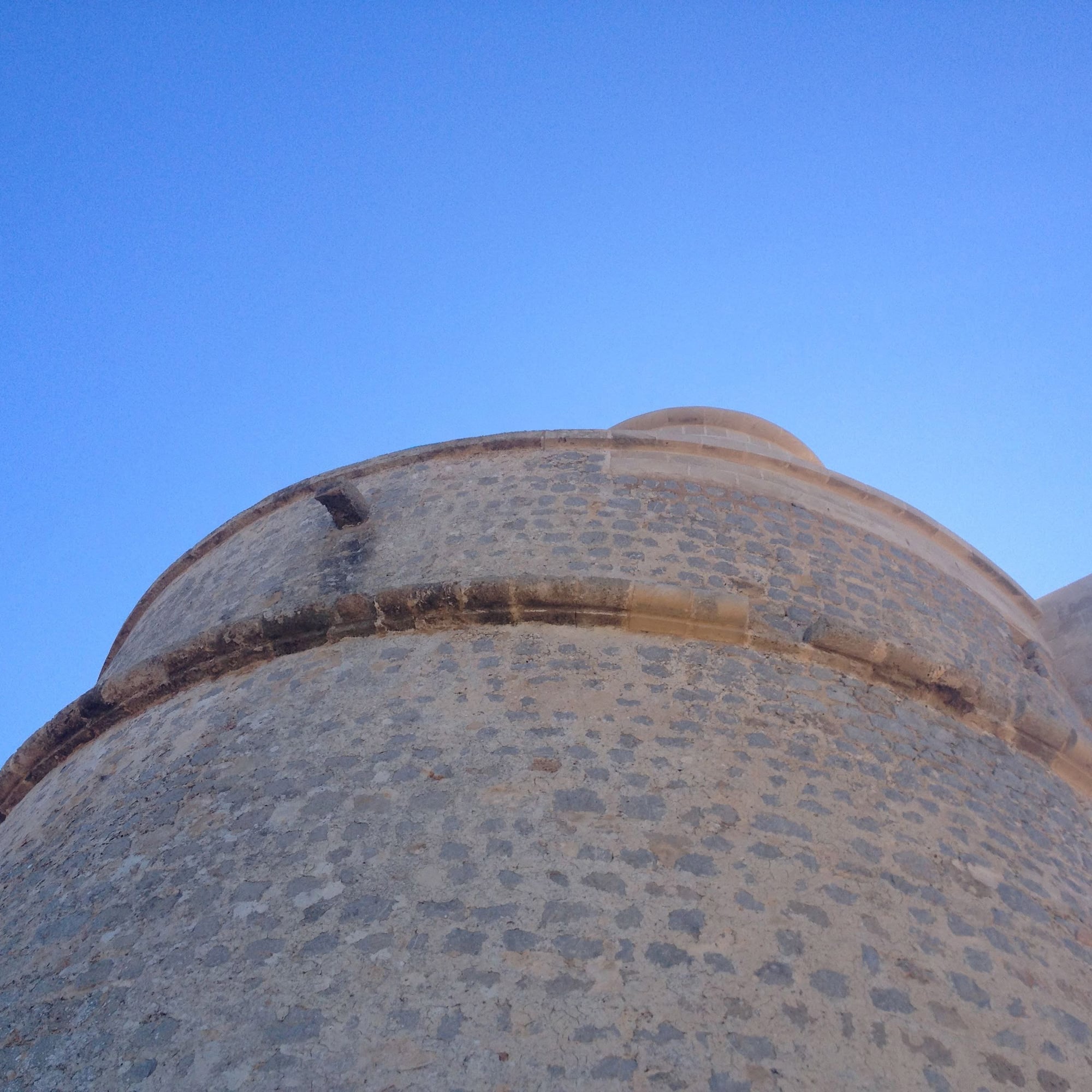 Historic stone watchtower against a bright blue sky.