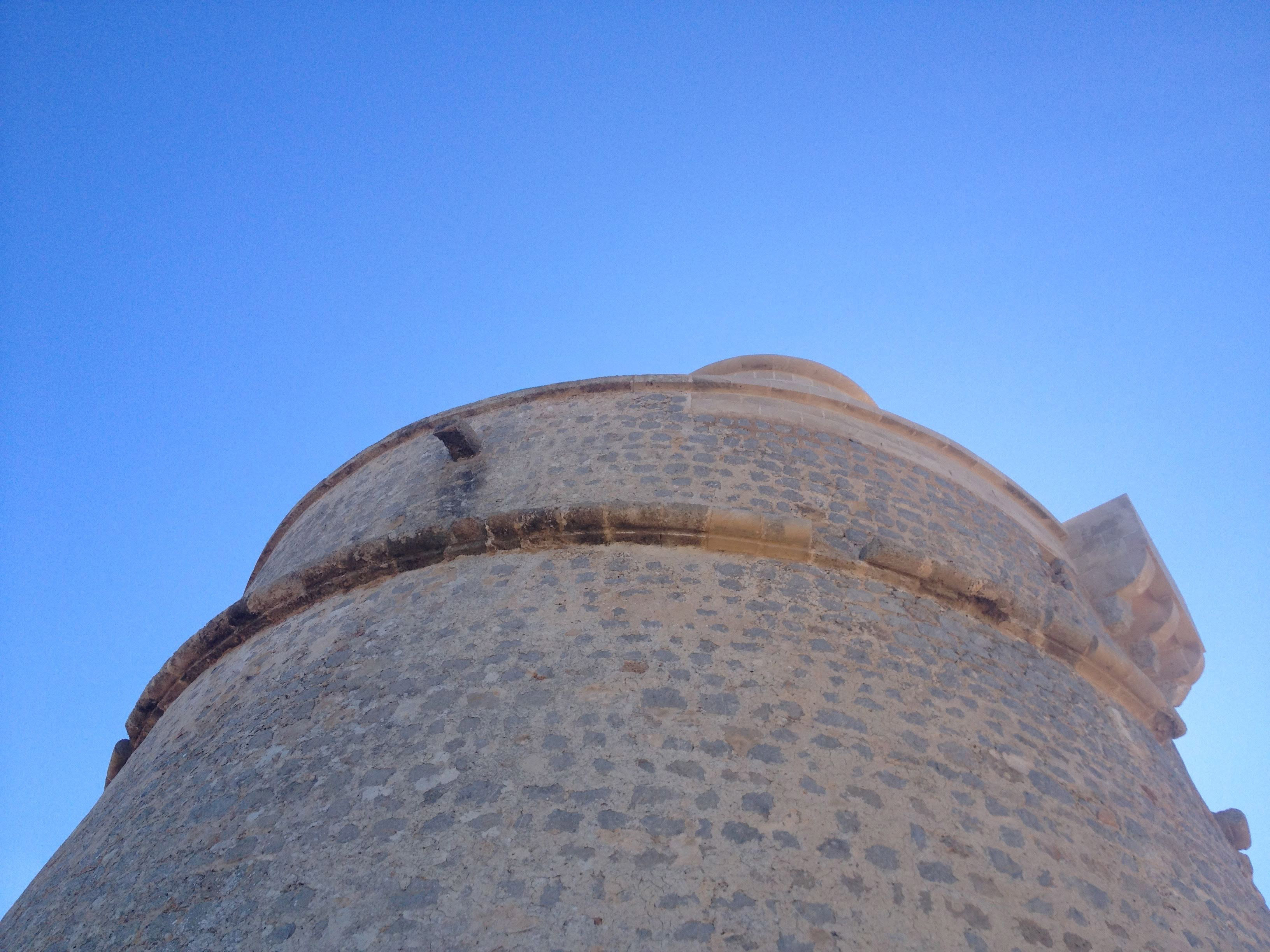 Historic stone watchtower against a bright blue sky.