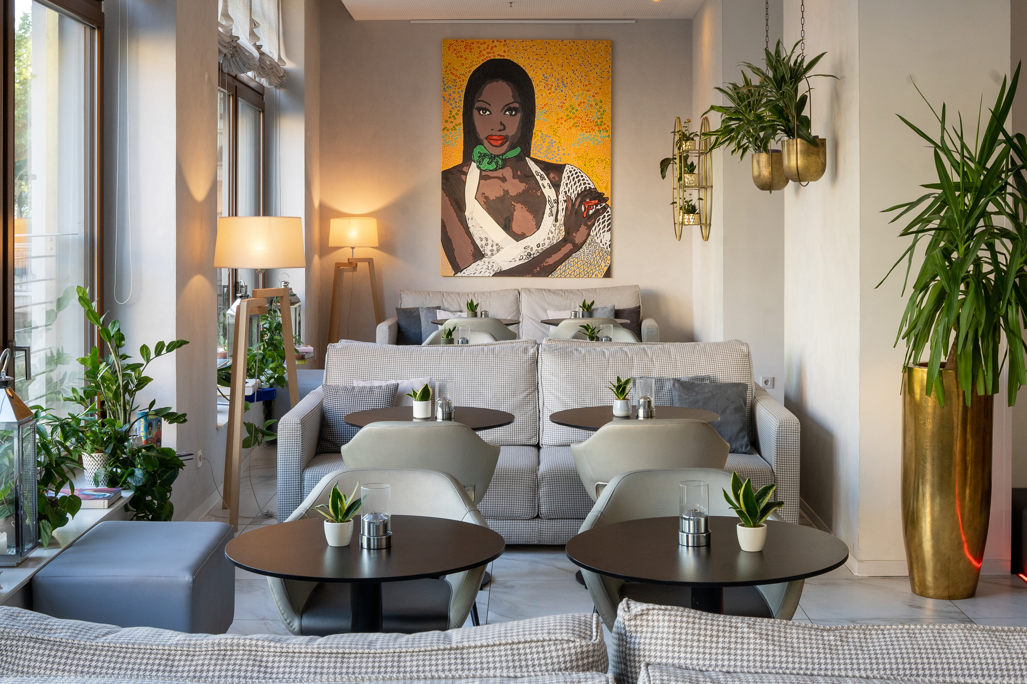 Modern hotel lounge with vibrant art, comfortable seating, and abundant plants.