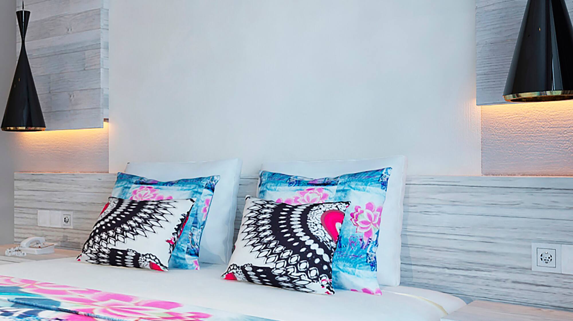 a bed with pillows and a lamp on the wall