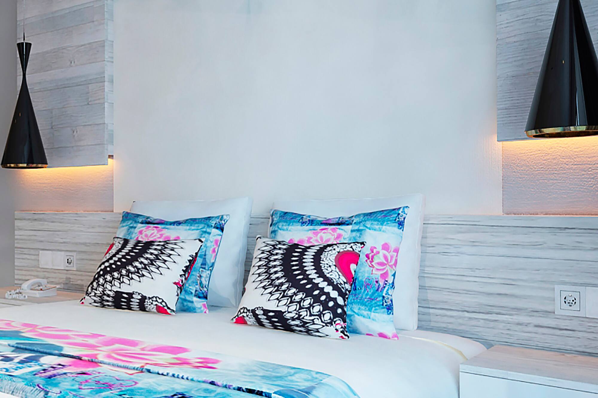 a bed with pillows and a lamp on the wall