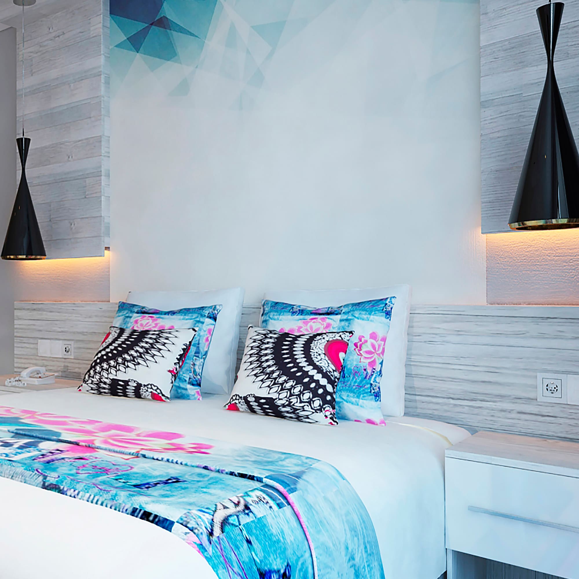 a bed with pillows and a lamp on the wall