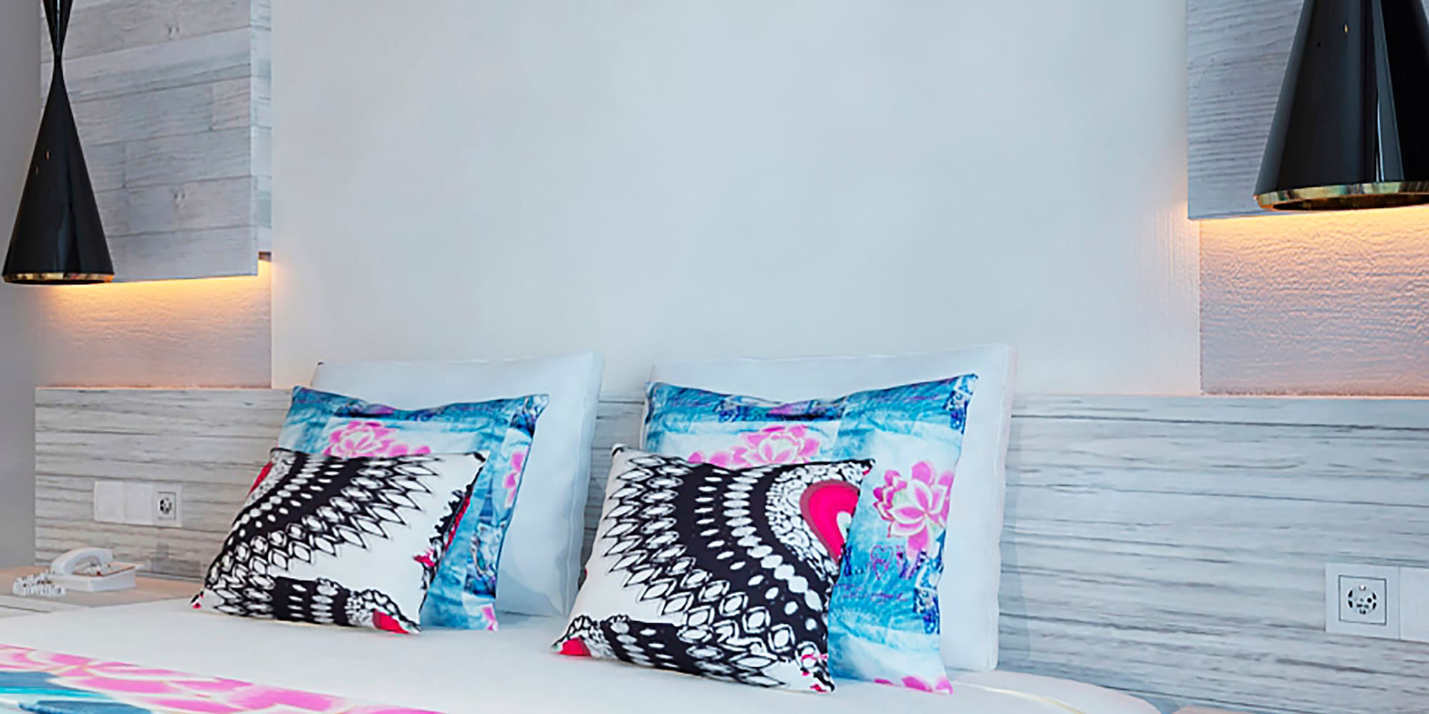 a bed with pillows and a lamp on the wall