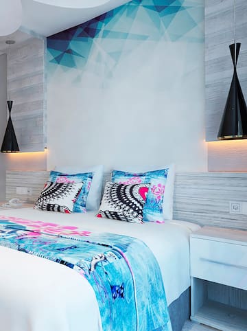 a bed with pillows and a lamp on the wall