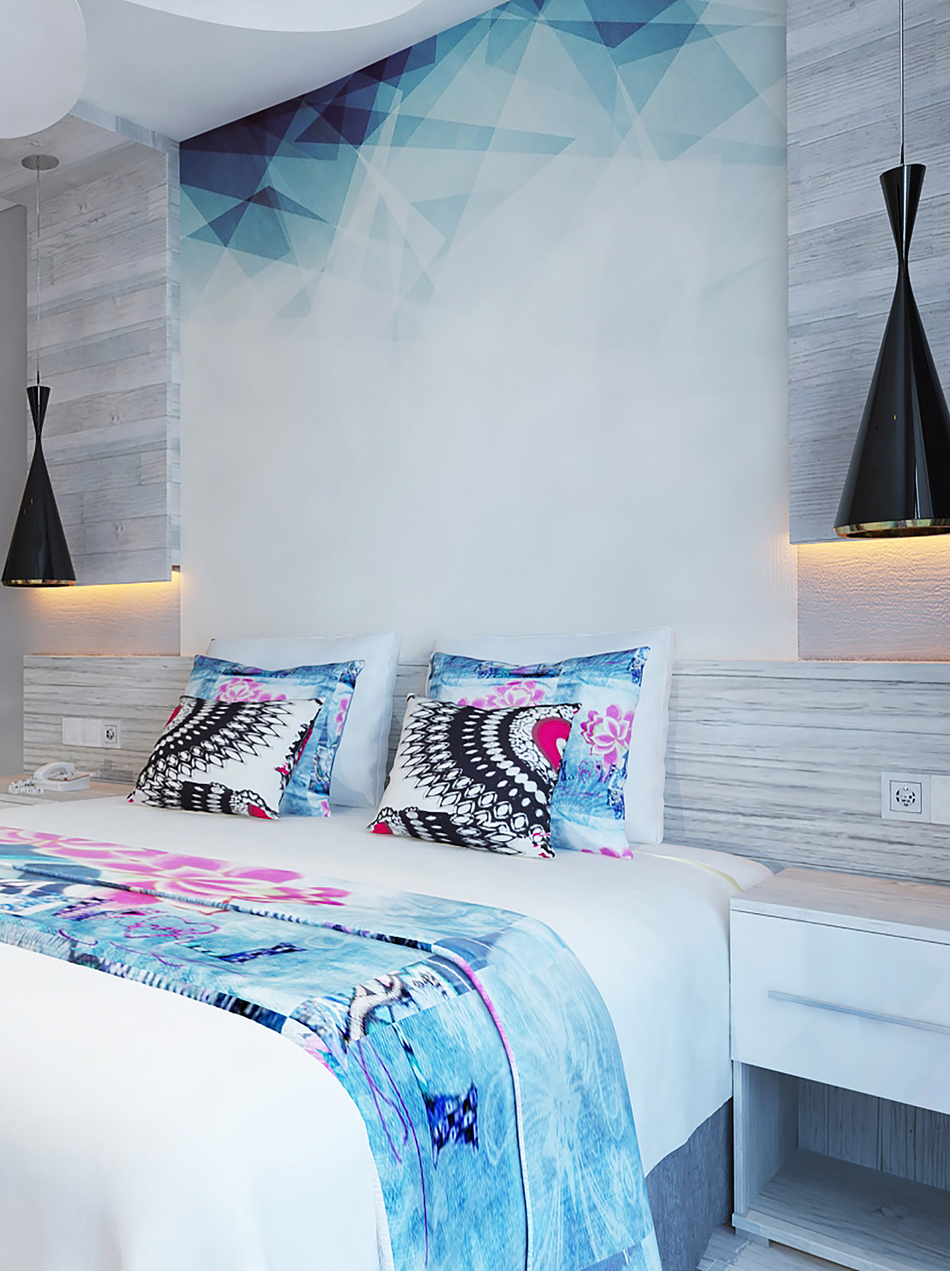 a bed with pillows and a lamp on the wall