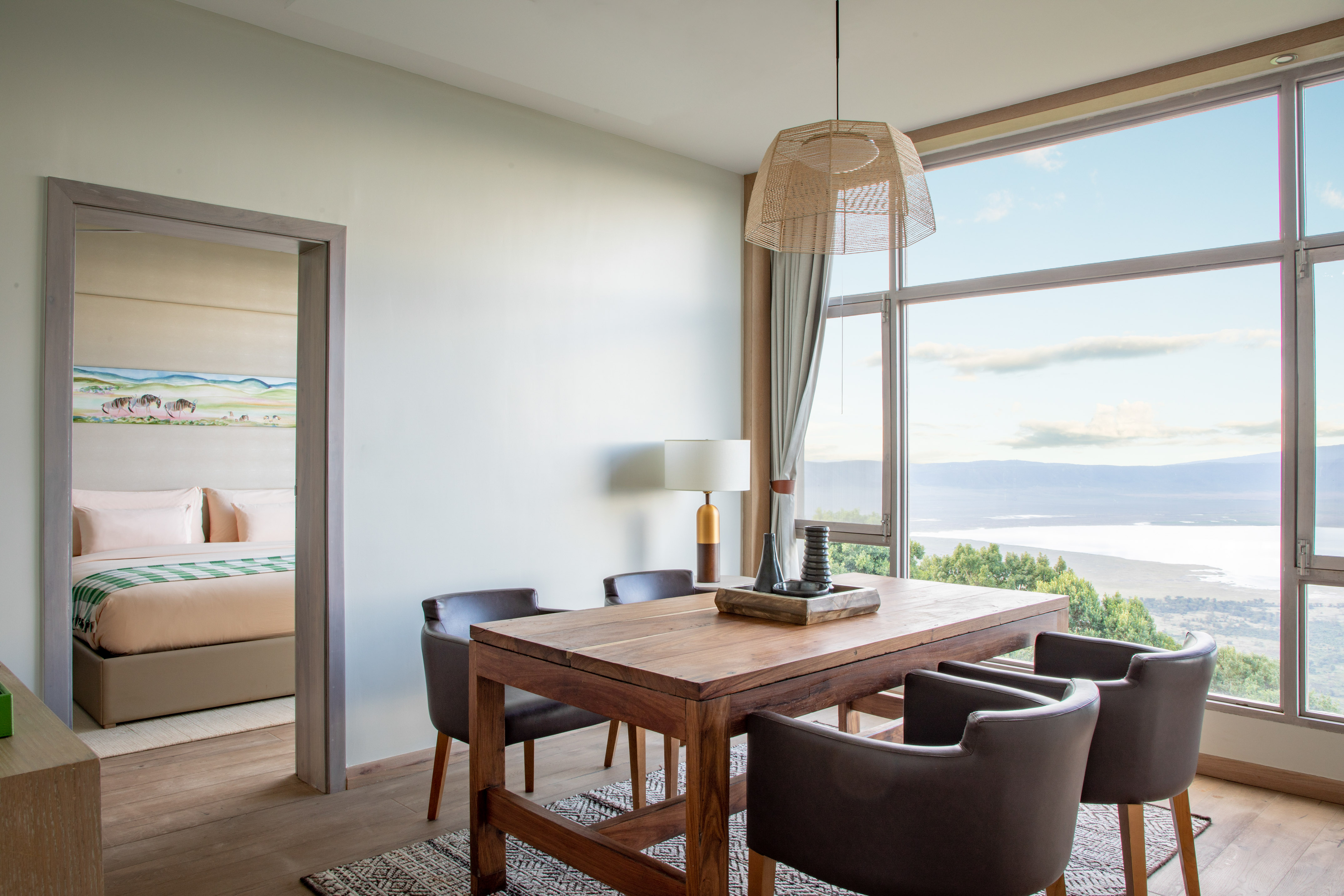 Luxury safari lodge dining room with panoramic lake view, adjoining bedroom.