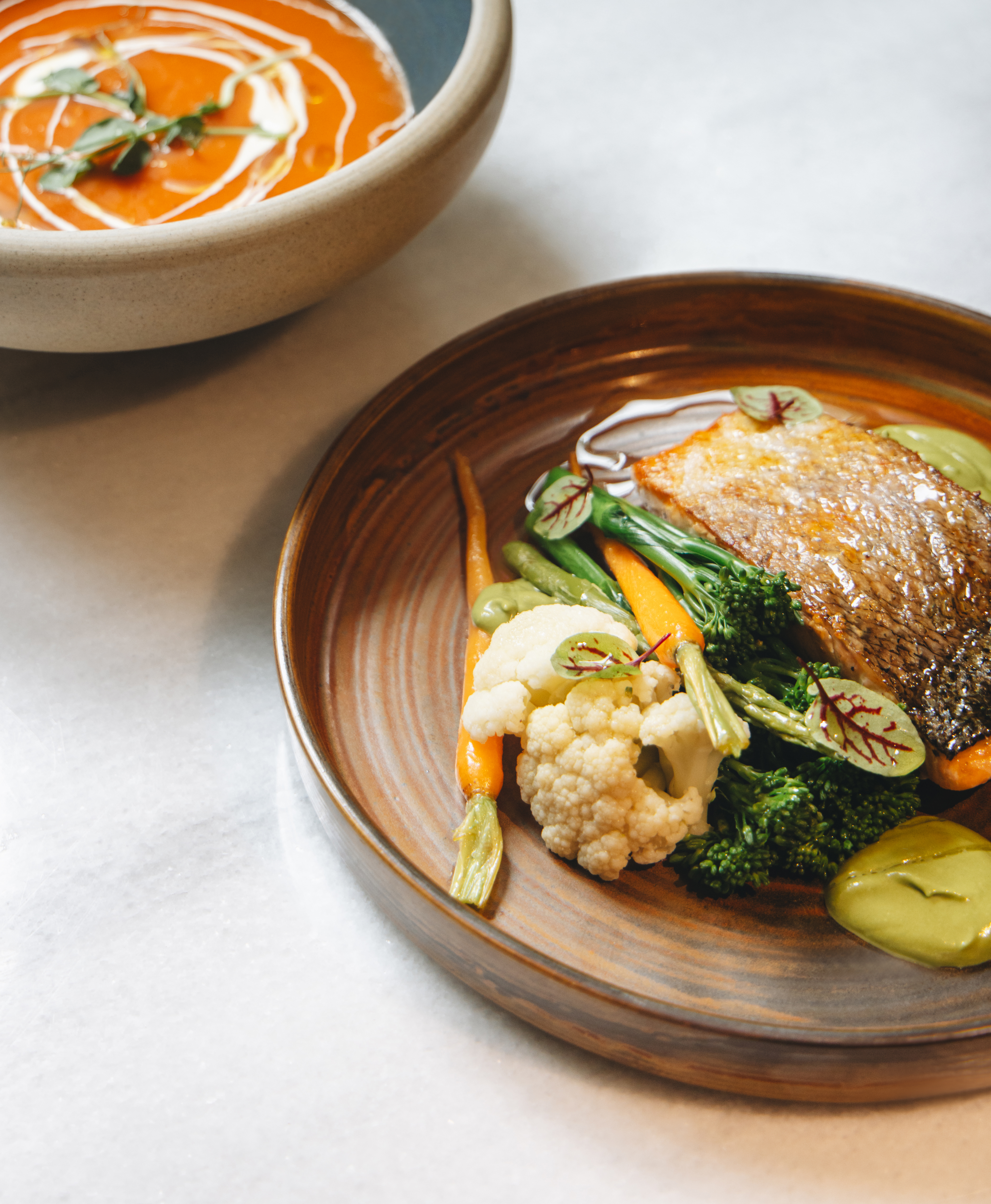 Pan-seared fish, carrots, broccoli, cauliflower, green sauce, and creamy tomato soup.