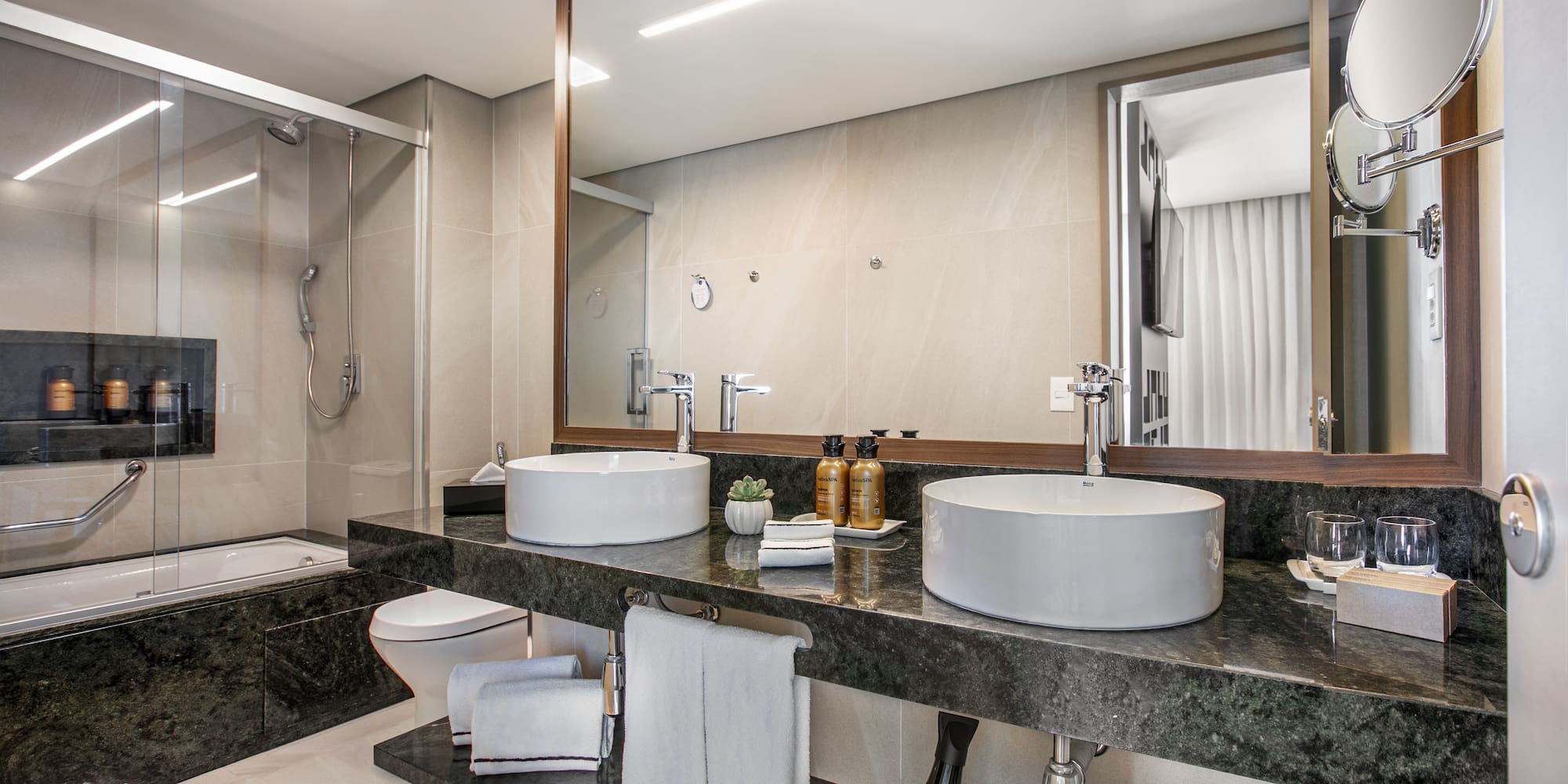 Modern luxury bathroom with double vessel sinks, granite vanity, shower, and bathtub.