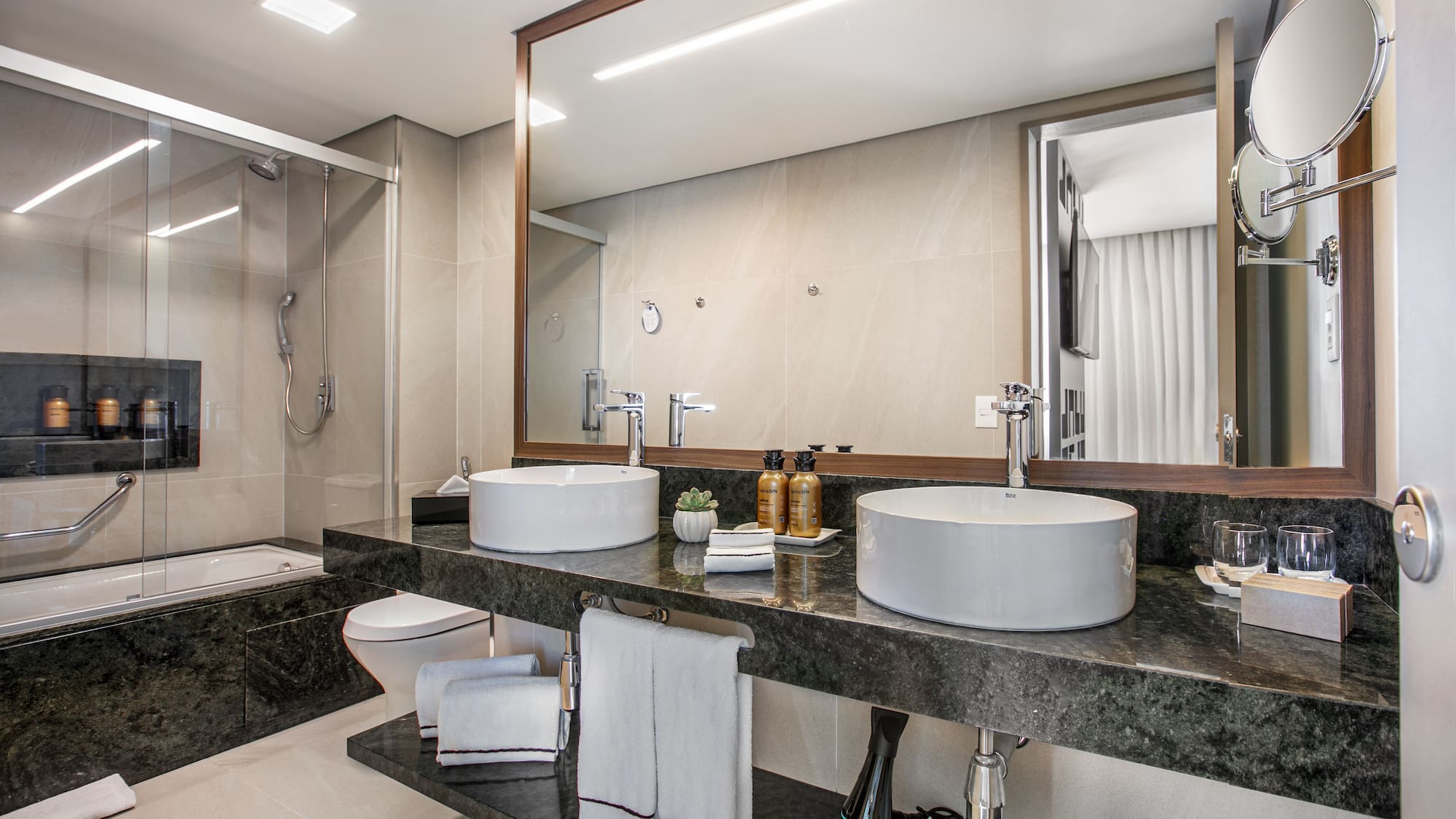Modern luxury bathroom with double vessel sinks, granite vanity, shower, and bathtub.