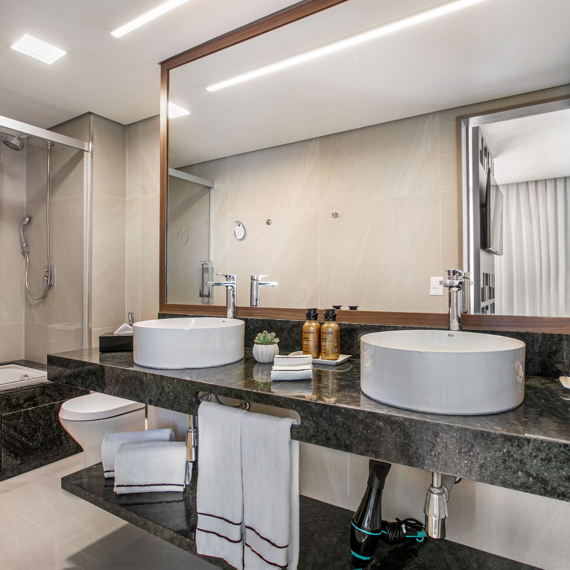 Modern luxury bathroom with double vessel sinks, granite vanity, shower, and bathtub.
