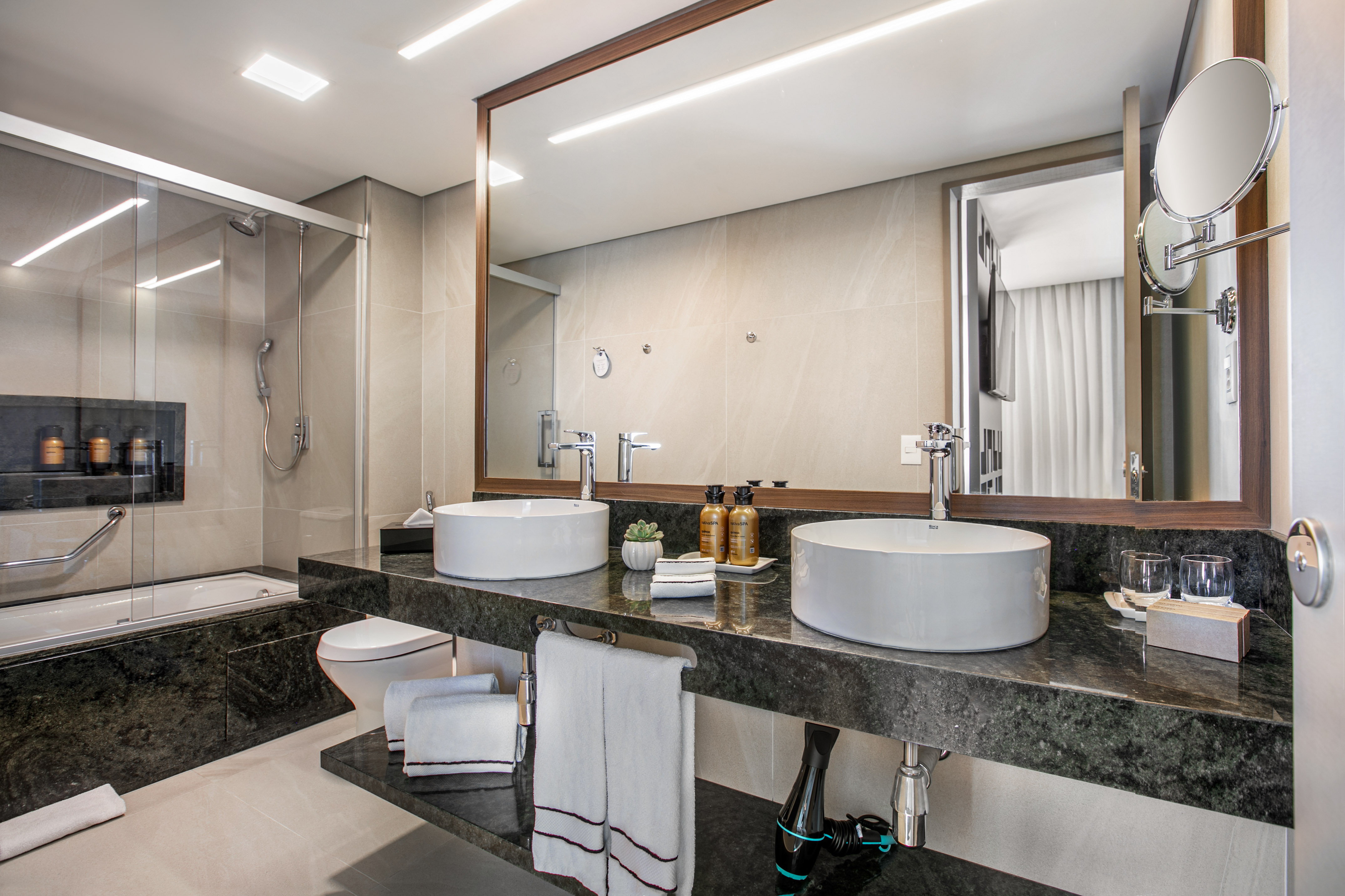 Modern luxury bathroom with double vessel sinks, granite vanity, shower, and bathtub.