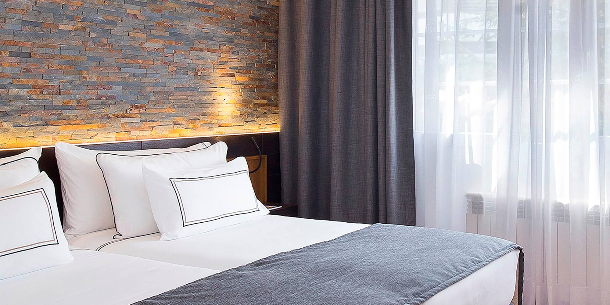 a bed with white pillows and a stone wall