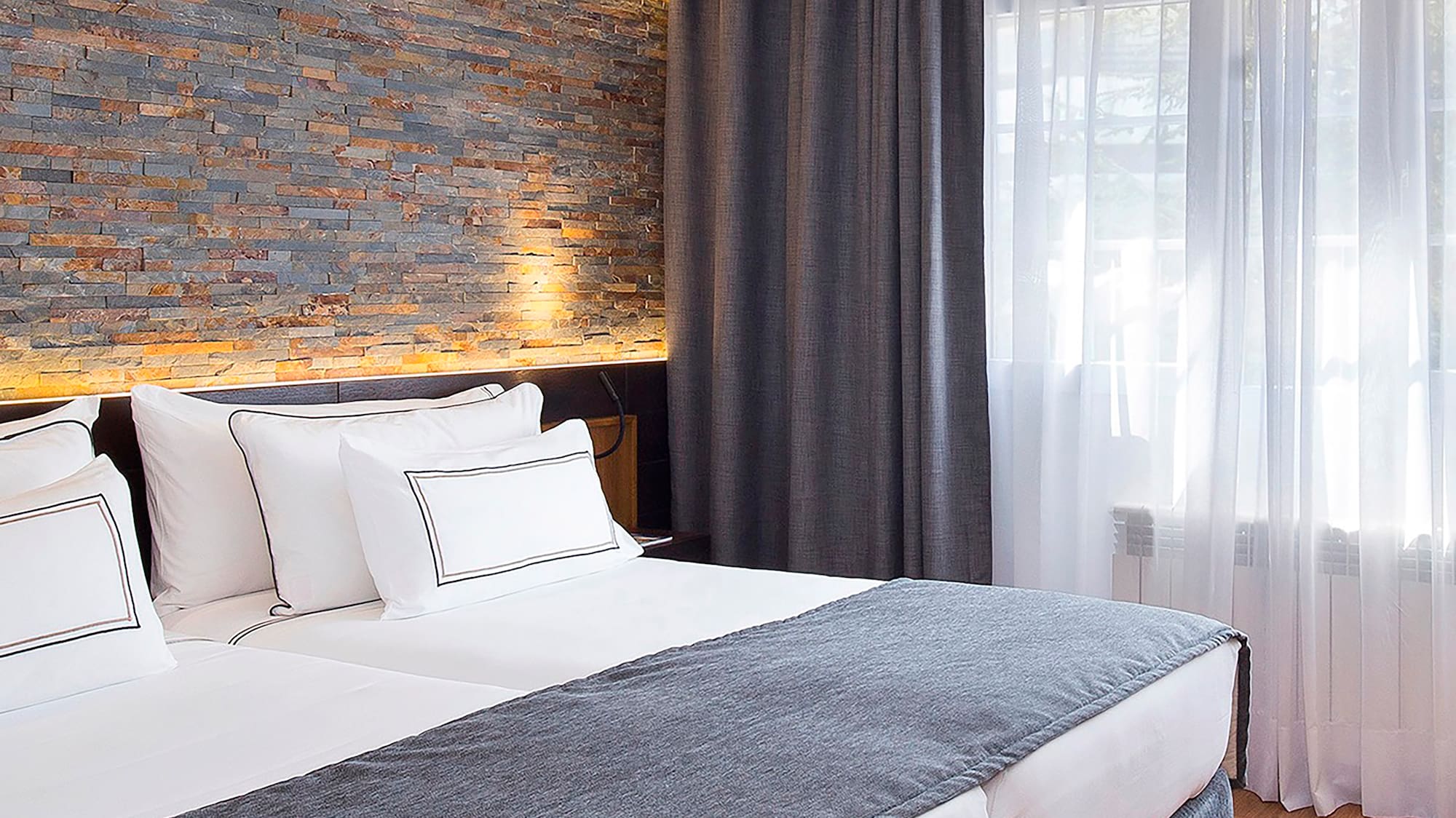 a bed with white pillows and a stone wall