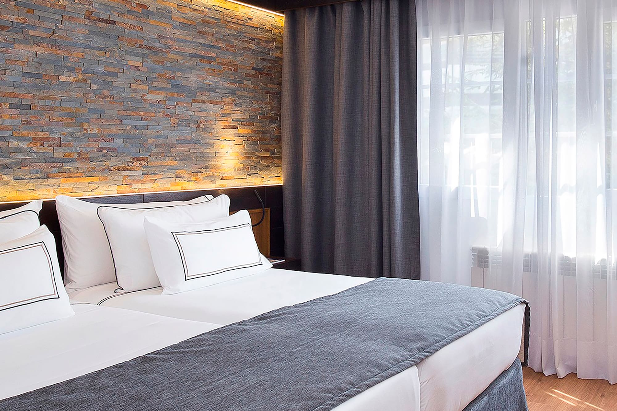 a bed with white pillows and a stone wall