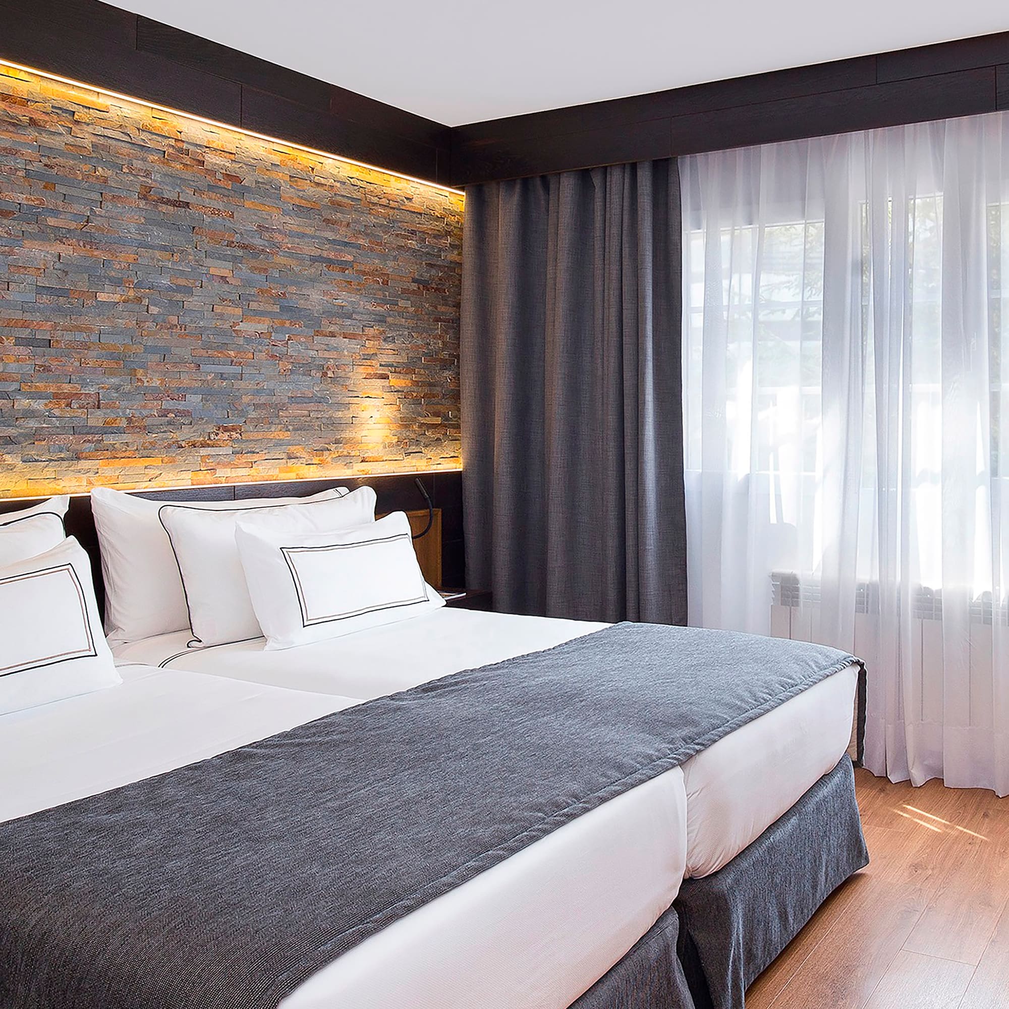 a bed with white pillows and a stone wall