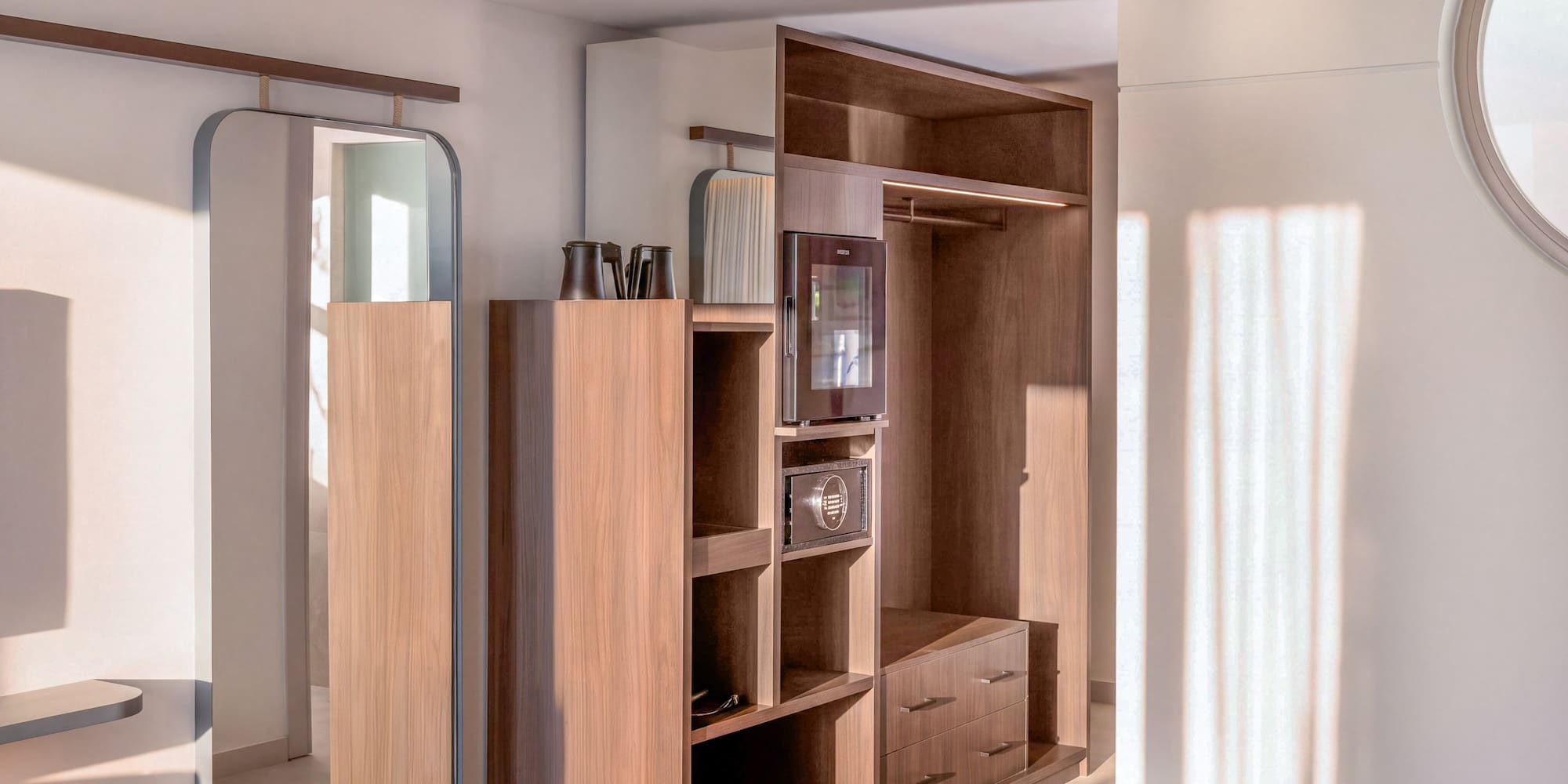Modern hotel room wardrobe with mirror, minibar, safe, and yoga mat. - INNSiDE Room بإطلالة جانبية على البحر - INNSiDE Bugibba, بوجيبا