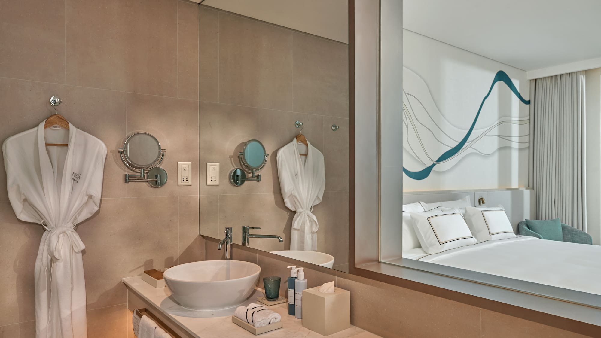 Contemporary hotel bathroom vanity with robes, mirror reflecting modern bedroom.