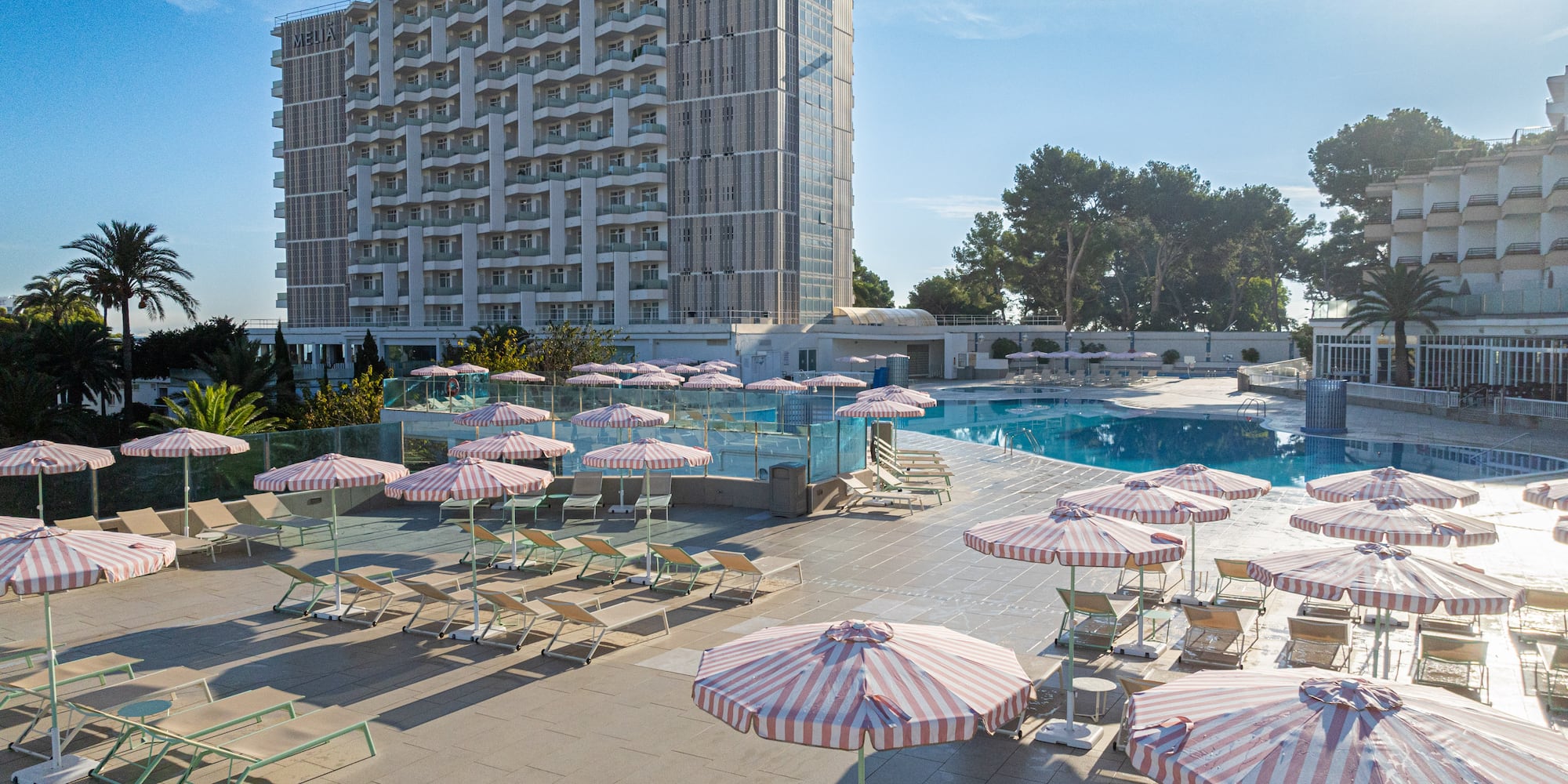 a pool with umbrellas and chairs and a building