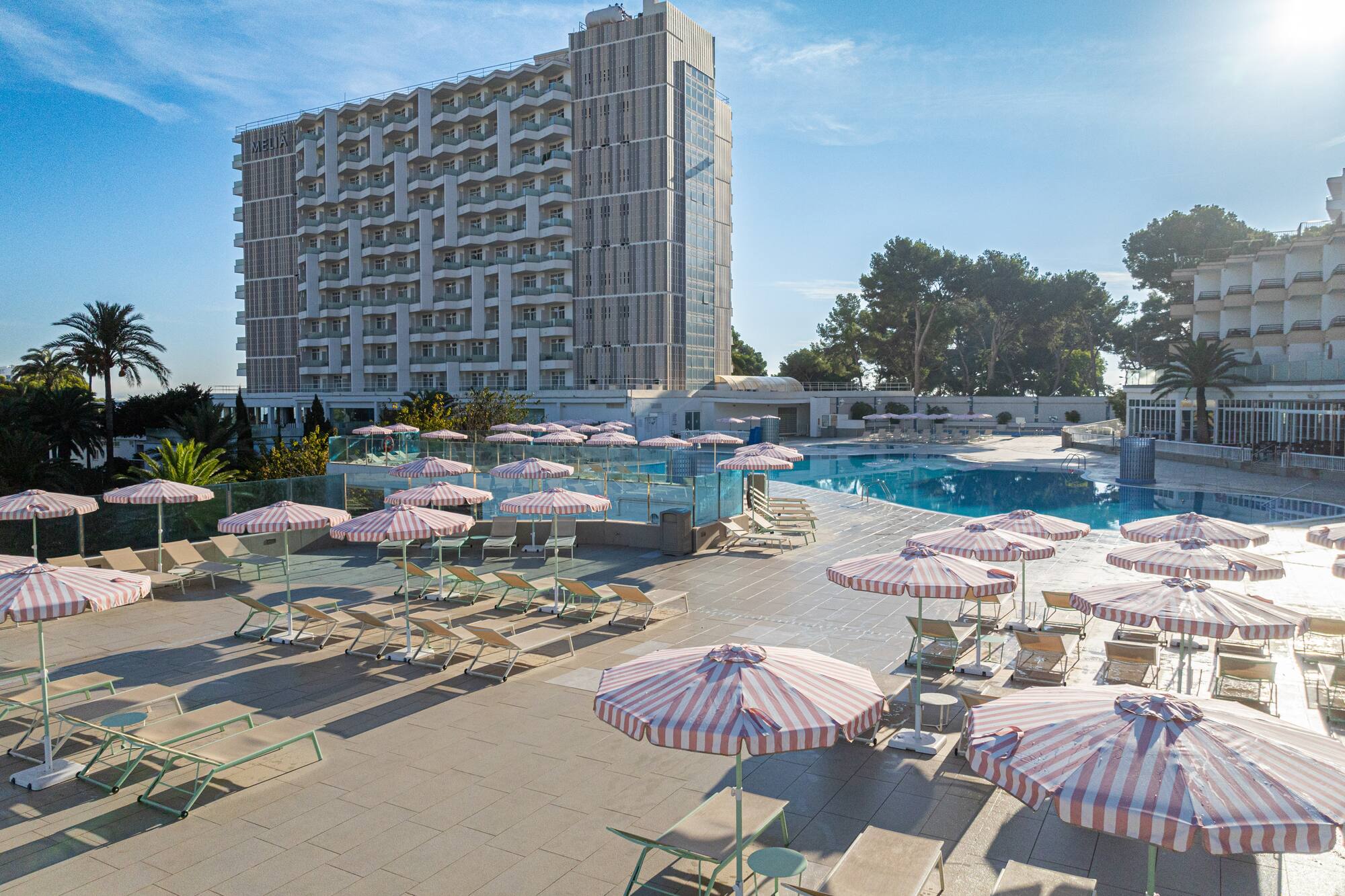 a pool with umbrellas and chairs and a building