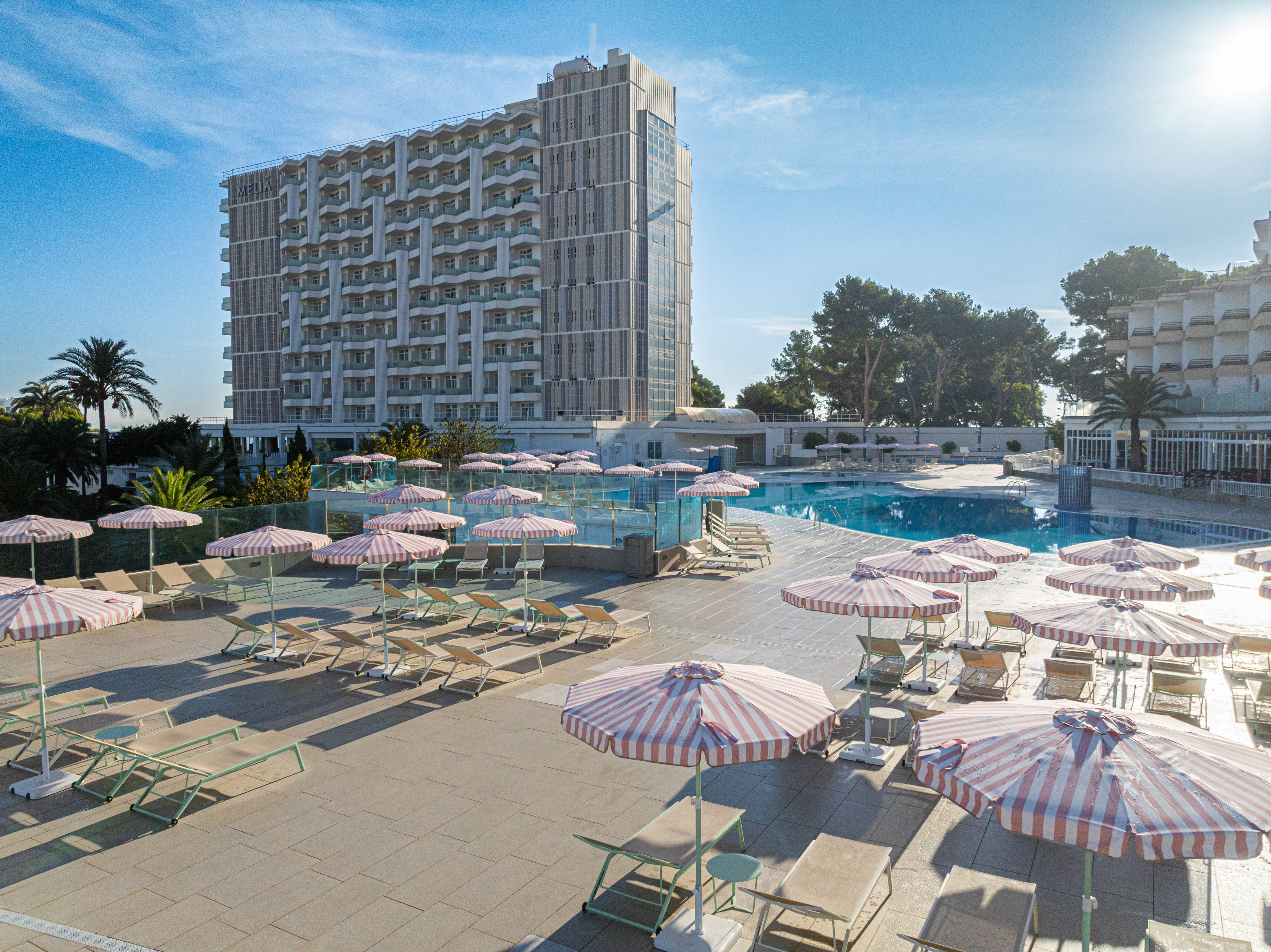a pool with umbrellas and chairs and a building
