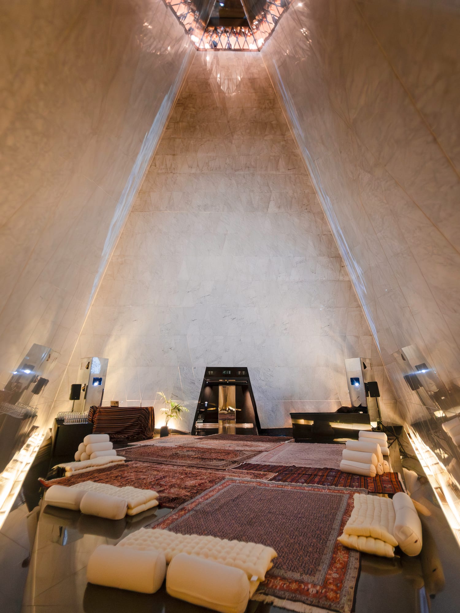 Modern pyramid interior with marble walls, traditional rugs, and lounge seating.