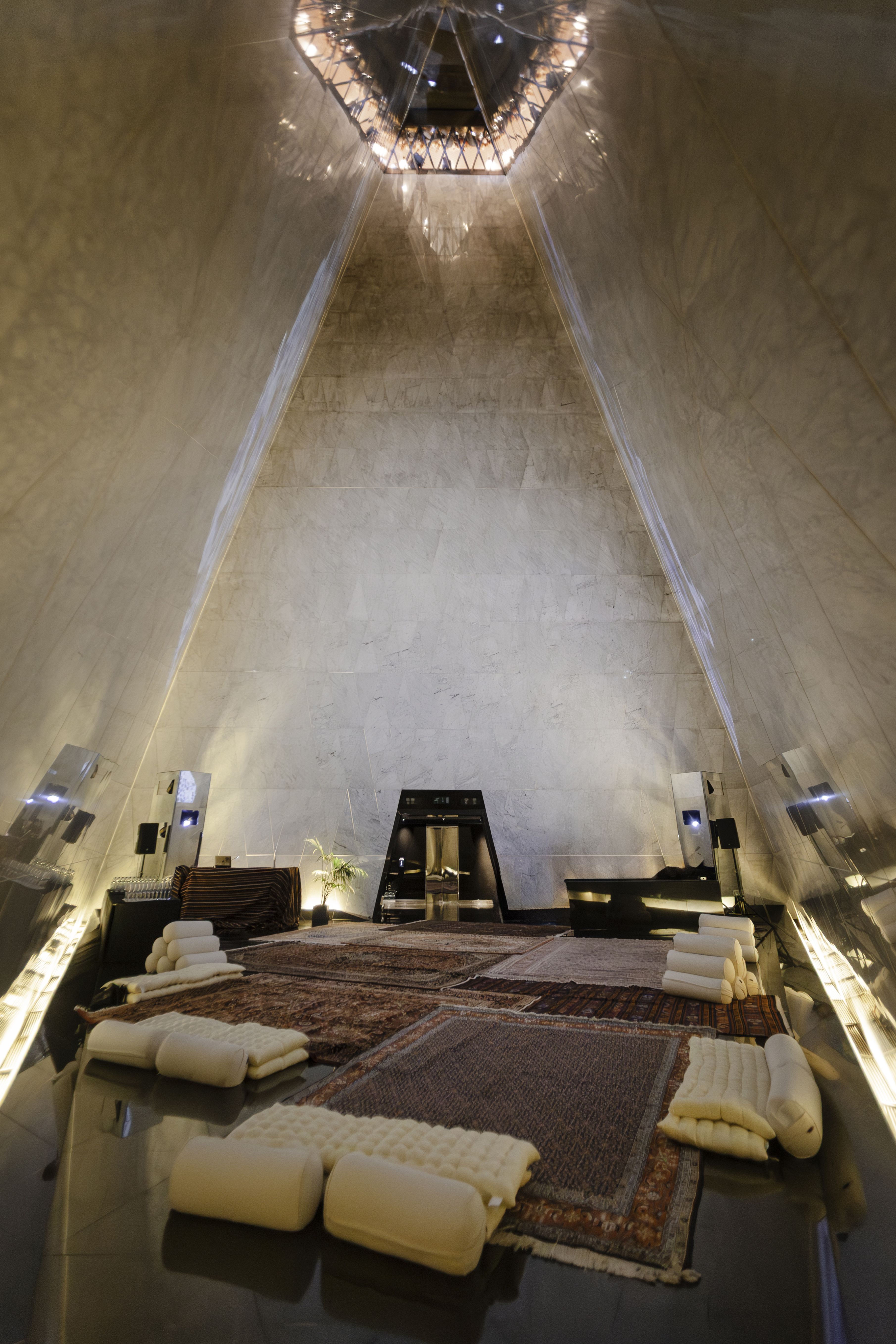Modern pyramid interior with marble walls, traditional rugs, and lounge seating.