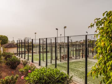 a tennis court with lights and trees