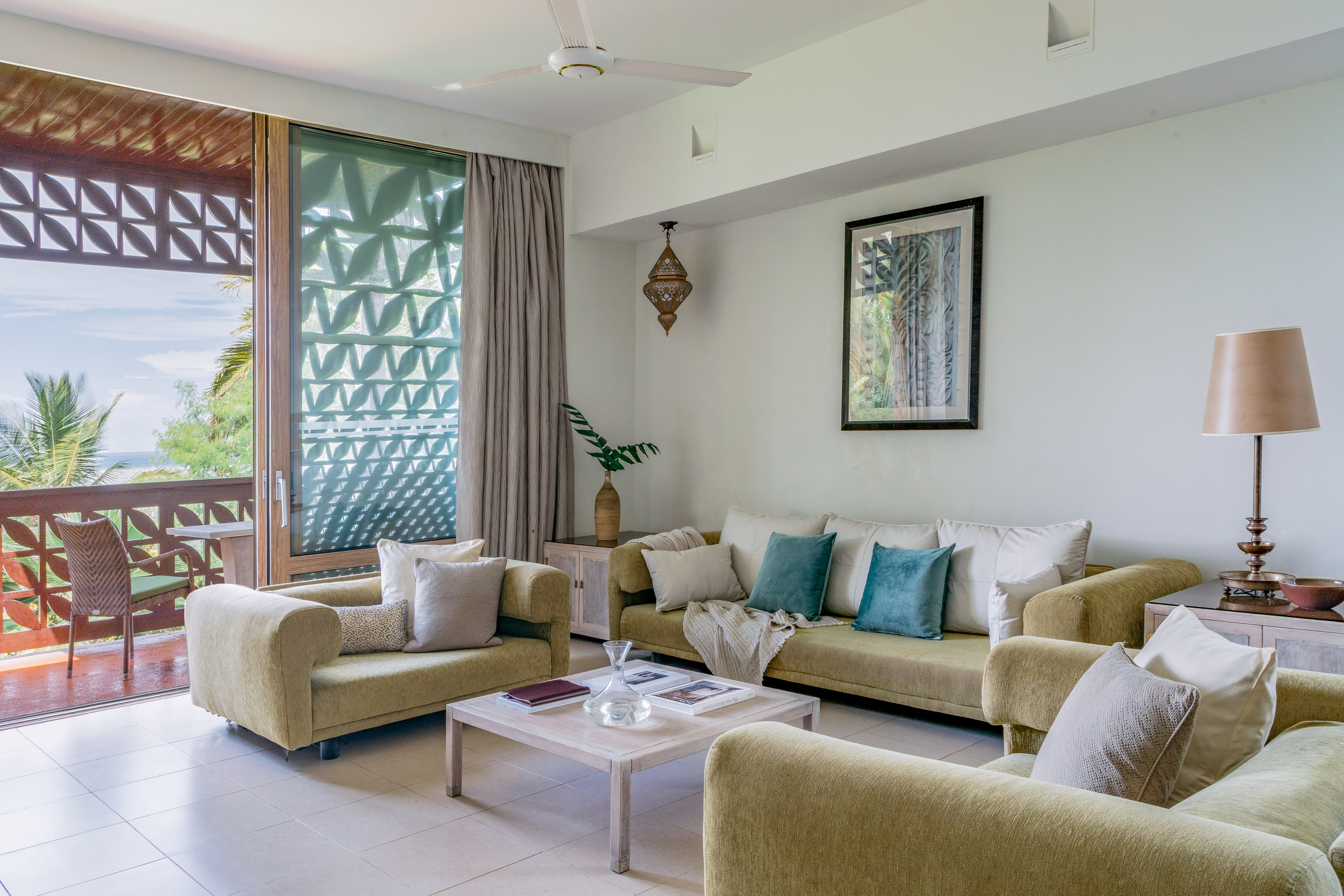 Modern tropical living room with ocean view balcony and light green couches.