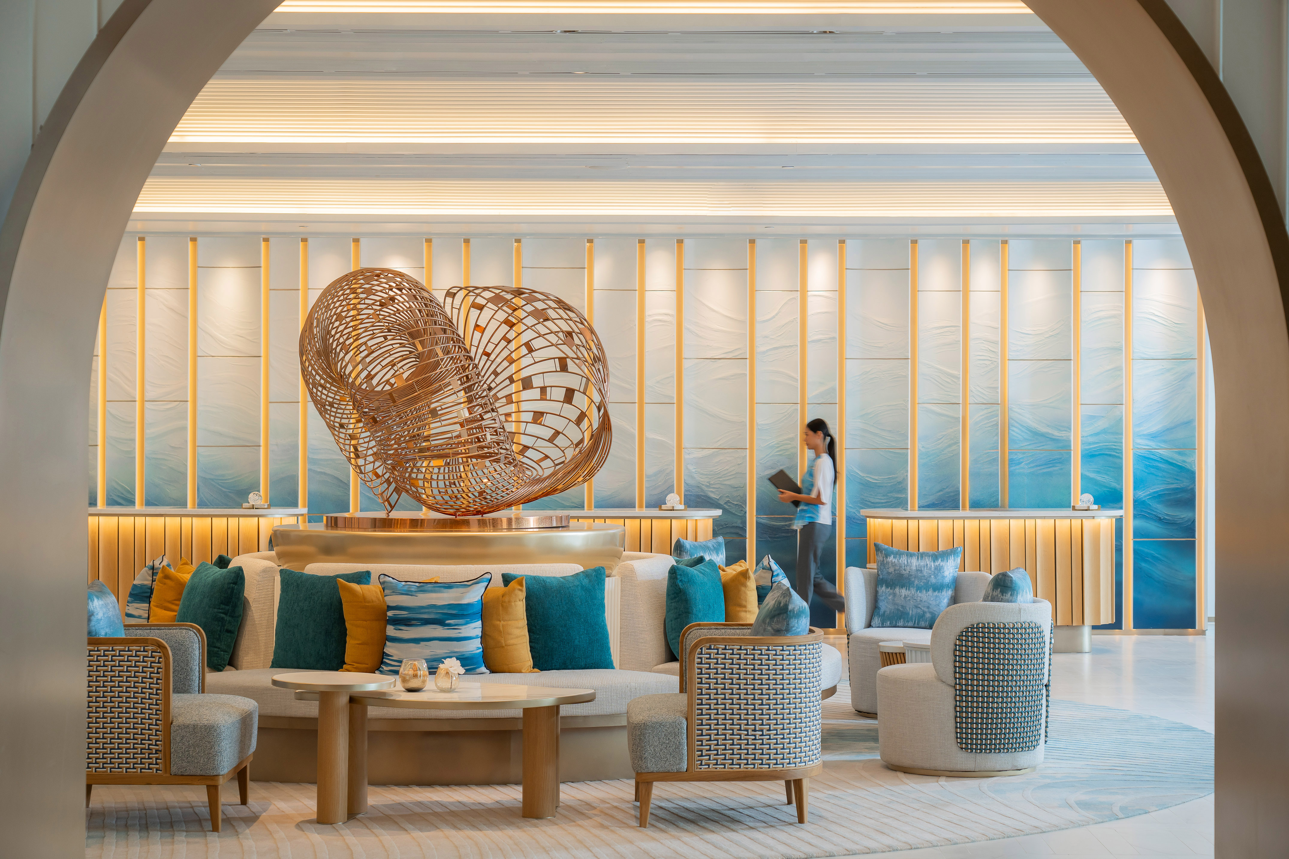 Luxurious hotel reception with abstract gold sculpture and blue wave wall.