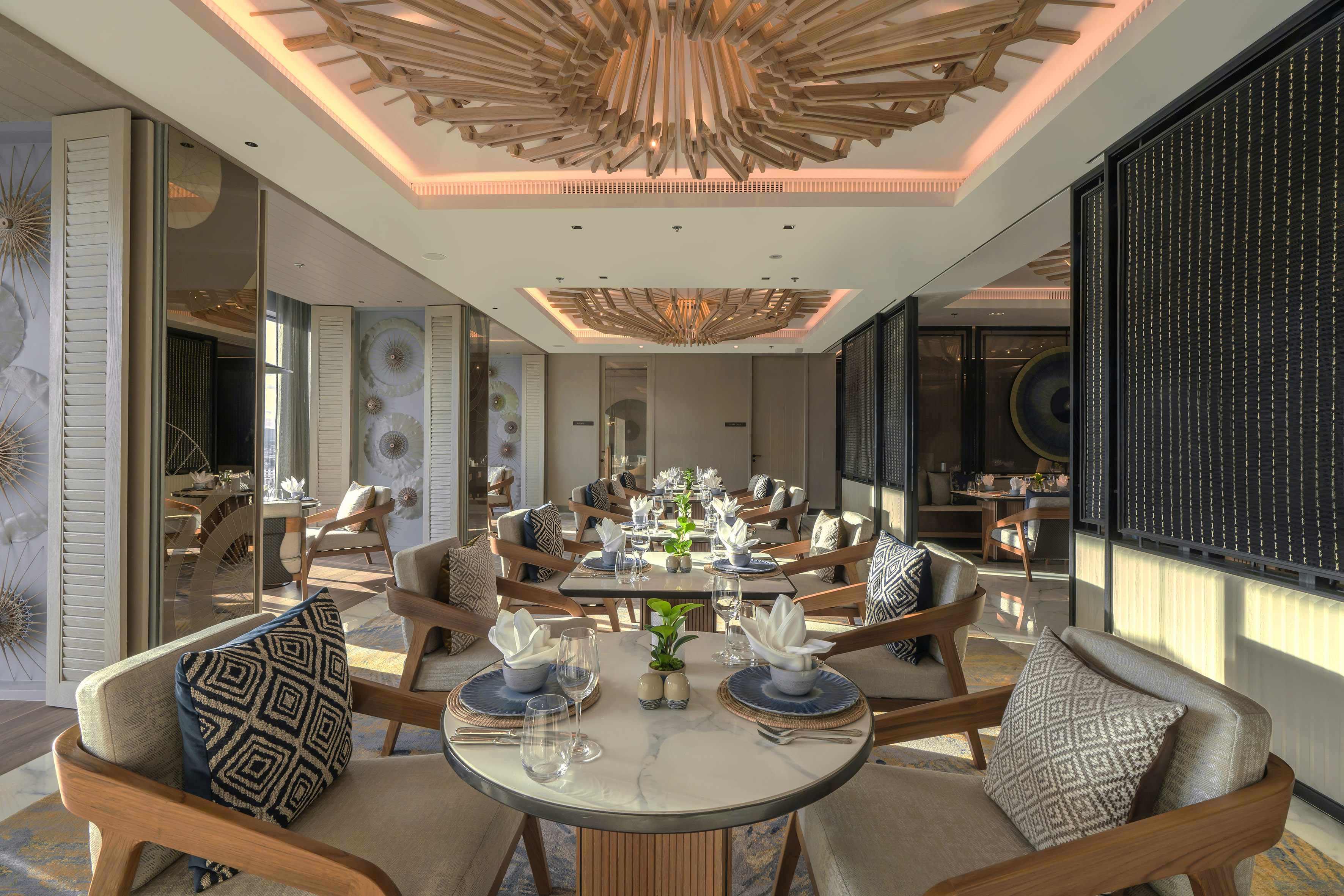 Elegant restaurant dining room, set tables with chairs, and unique wood chandelier.