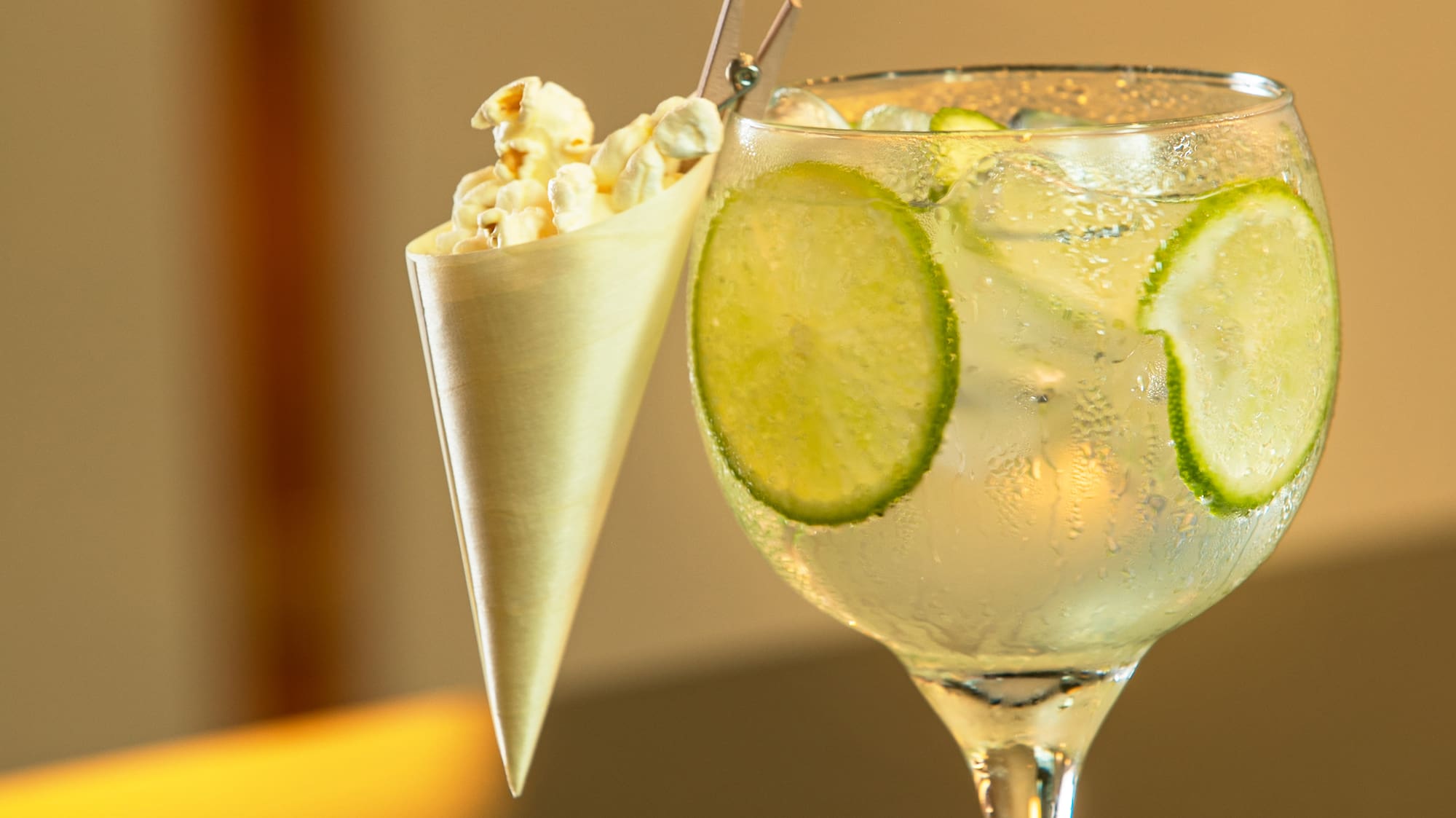 a glass of liquid with ice and popcorn in a cone